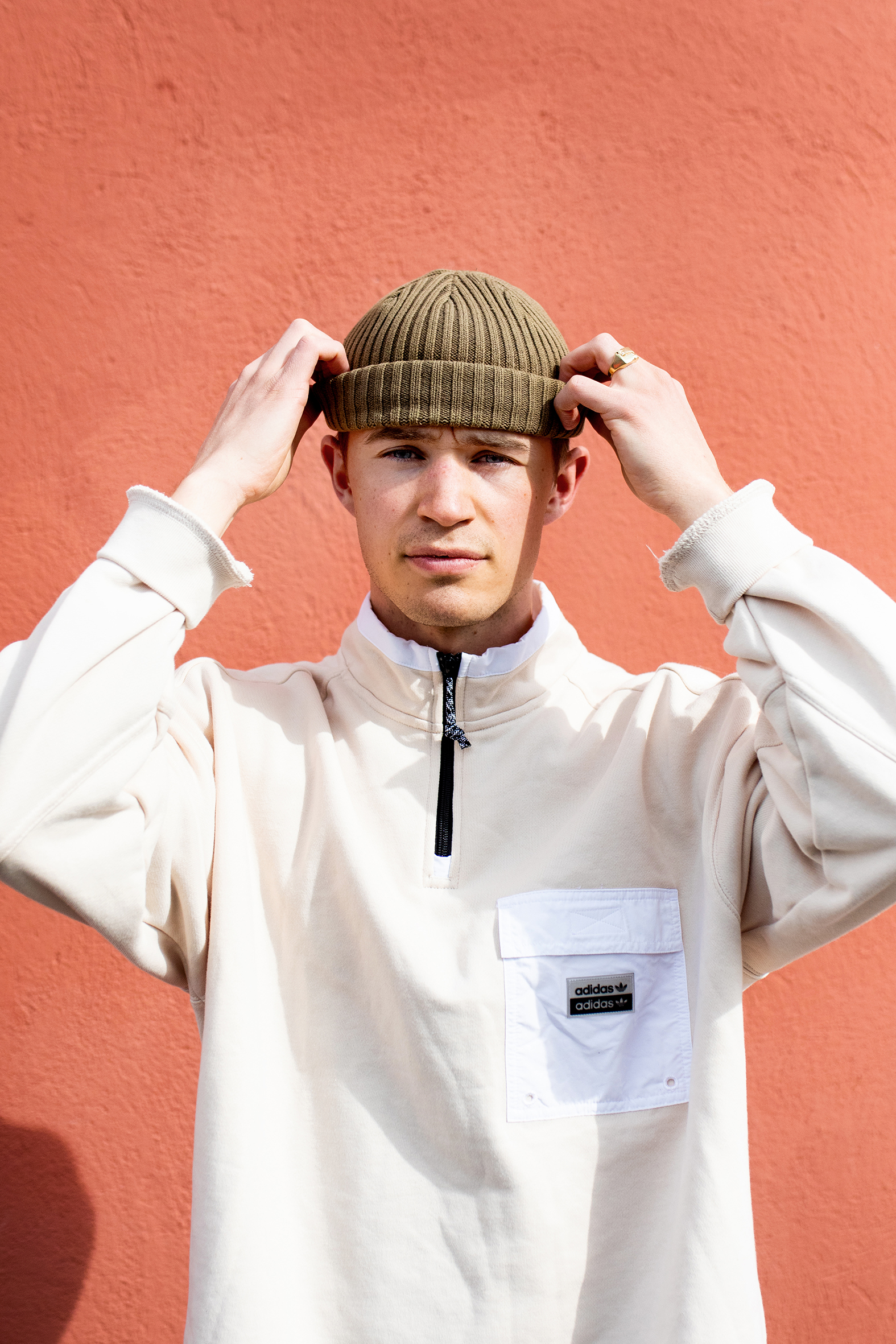 Martin i grønn lue og hvit genser foran en orange vegg