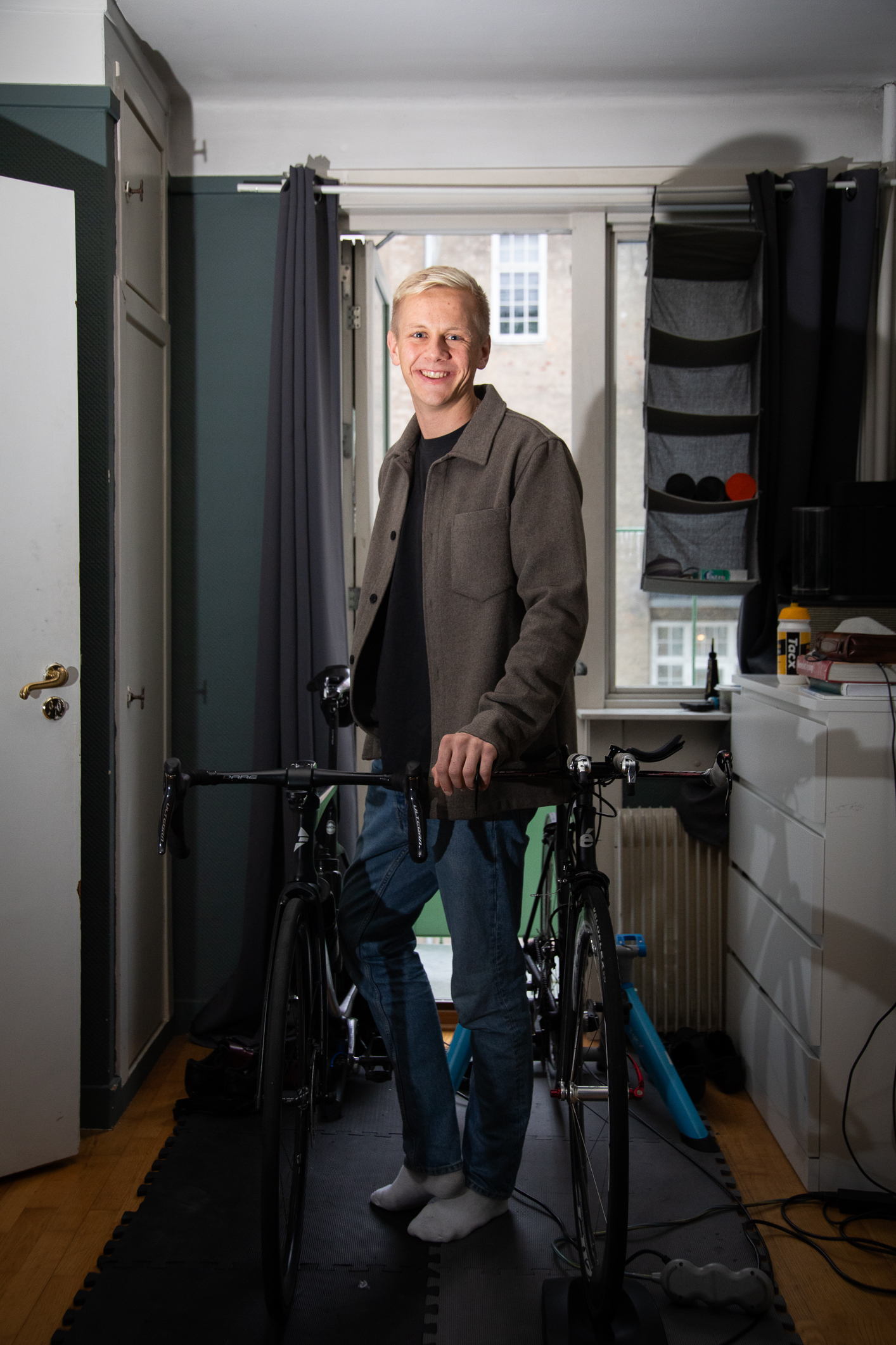 Den unge mannen på en matte i leiligheten mellom to racersykler.