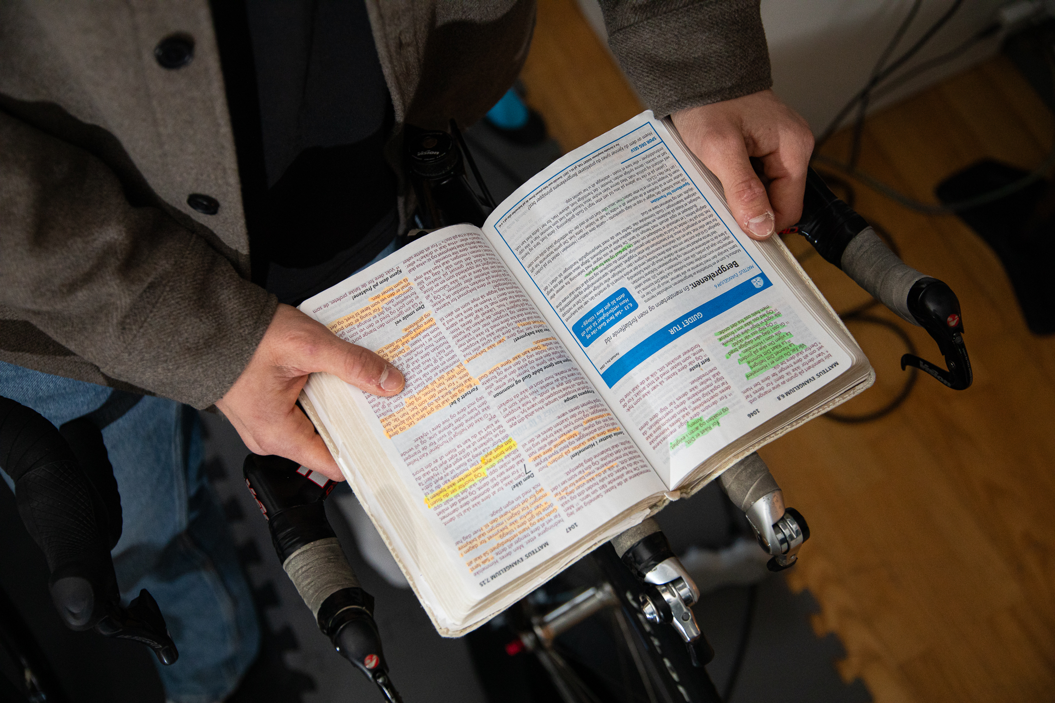 To hender som holder en bilbel. Den har mange blokker med understreking av tekst i flere farger.