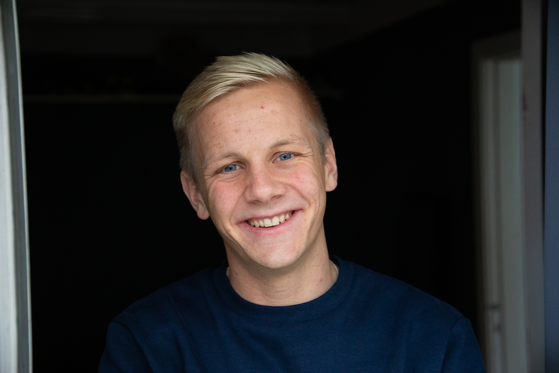 Ung mann som smiler mot kamera. Fotografert fra brystet og opp.