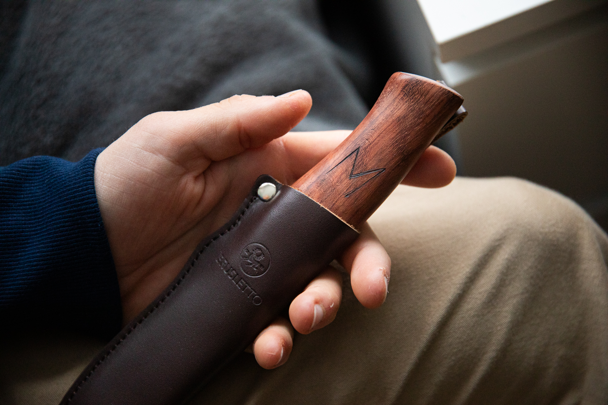 Hånd i fanget som holder en trekniv i slire.