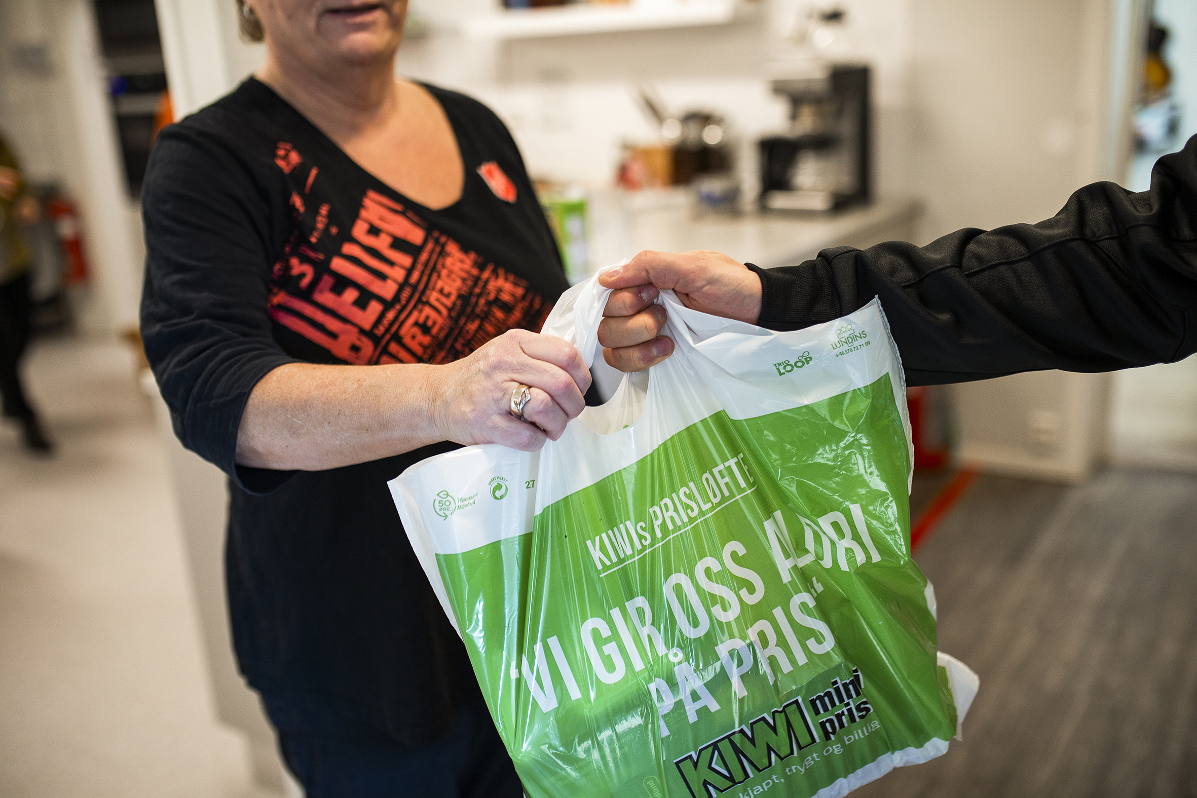 Bilde av en pose med matvarer som mottas av en person. Kan bare se hender og kropp – ikke hoder.