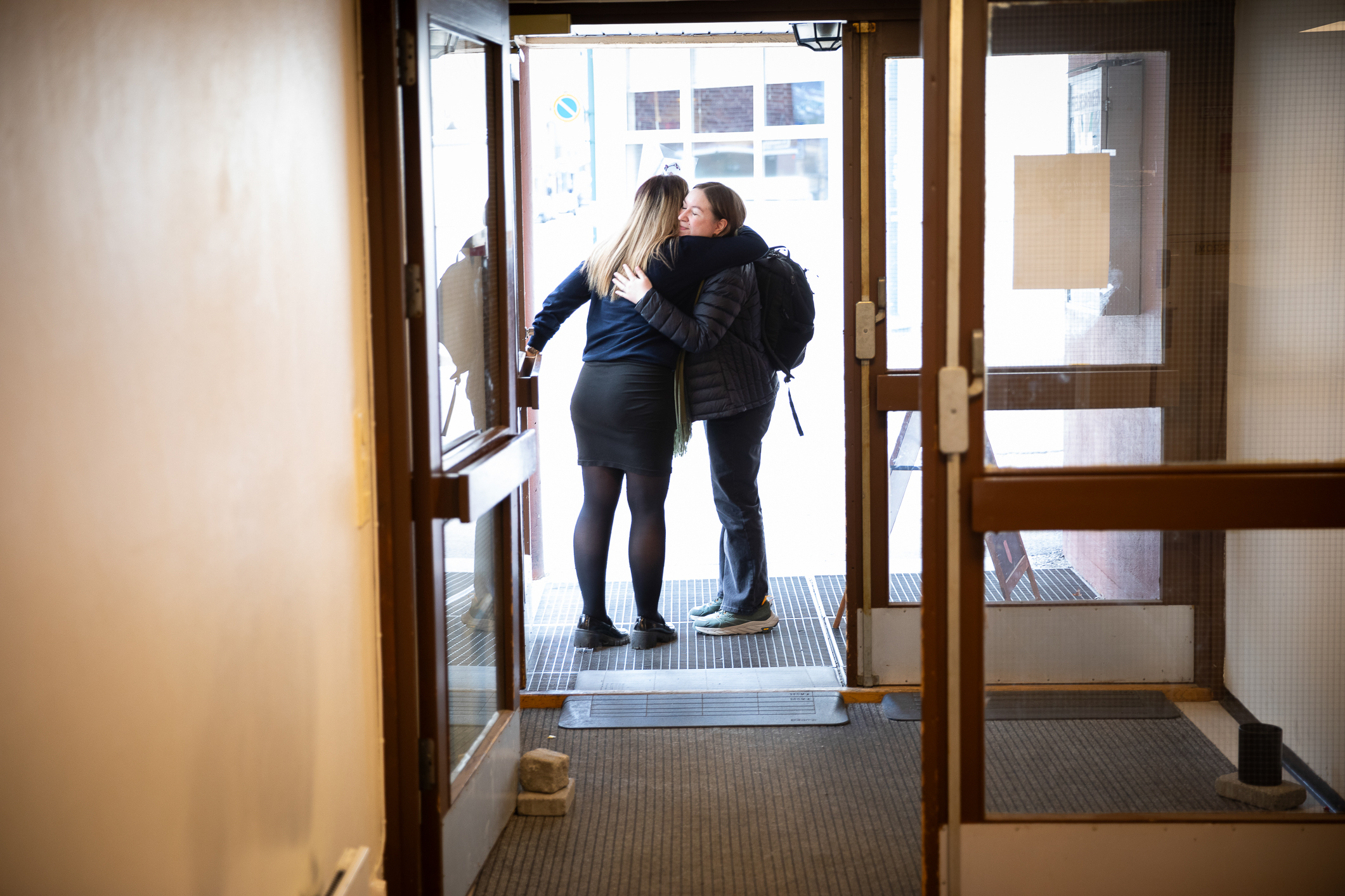 Foto: To kvinner som klemmer hverandre like utenfor en inngangsdør. Motivet er fra innsiden.