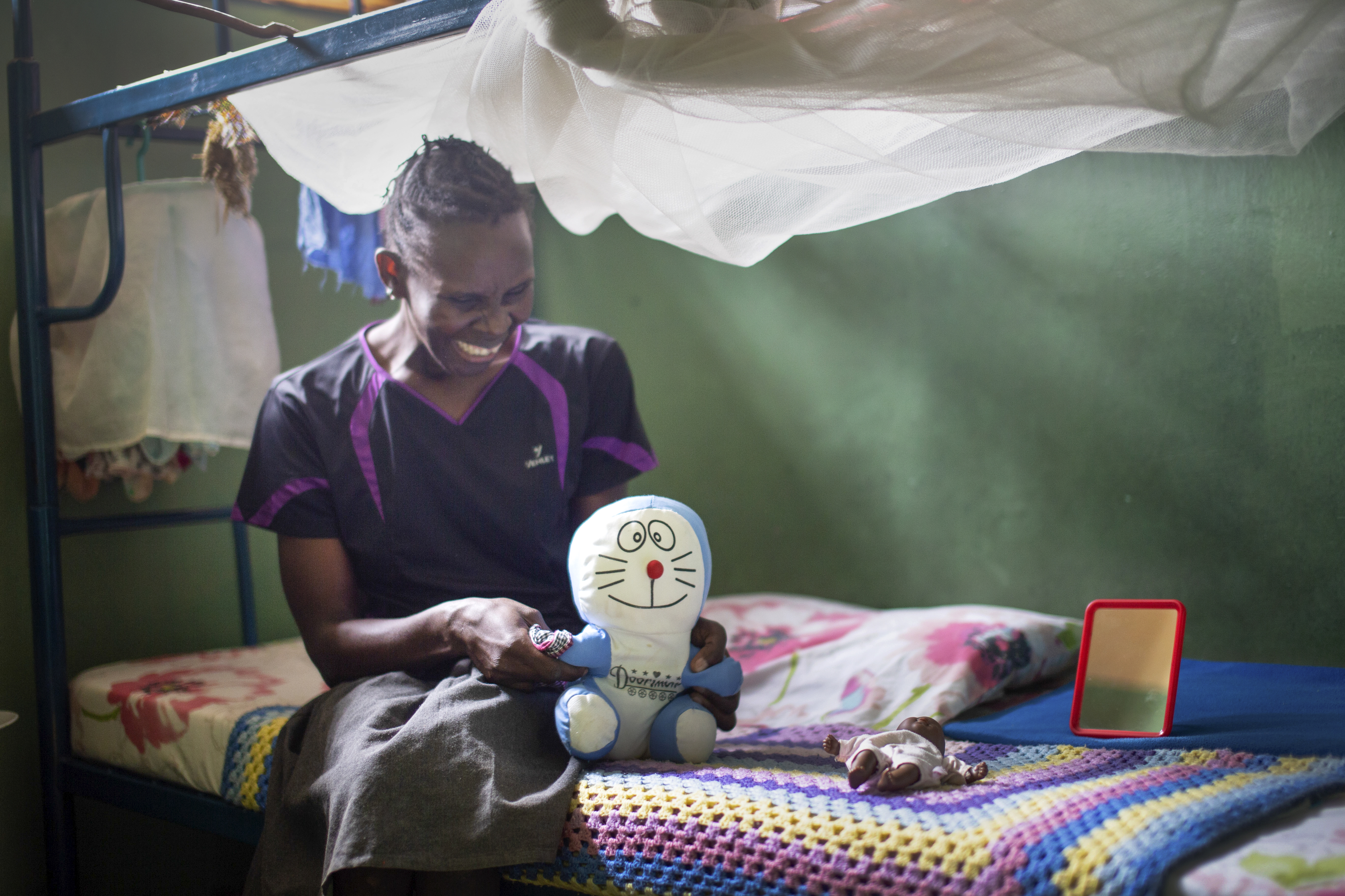 Bilde 1 viser Milly som sitter på sengen sin og smiler mens hun holder en bamse. Bilde 2 viser en annen bamse som ligger på sengen.