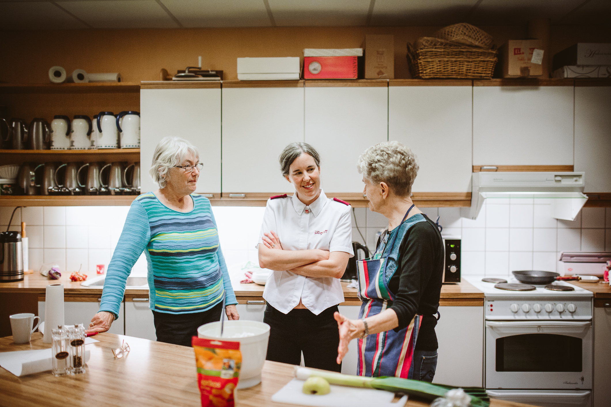 Miriam snakker med damer på kjøkkenet.