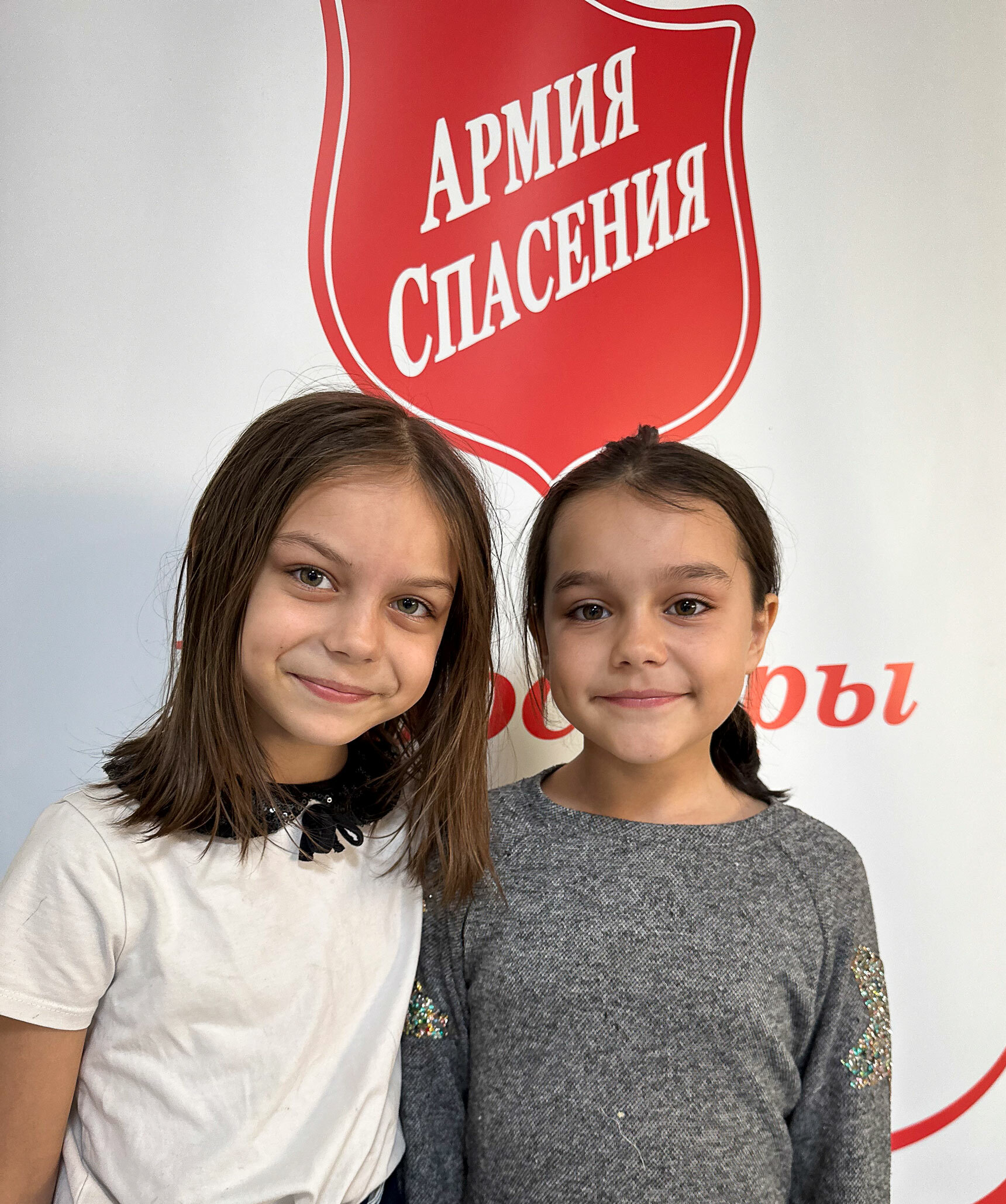 Foto: To småskolejenter står under Frelsesarmeens skilt som er skrevet med kyrilliske bokstaver.