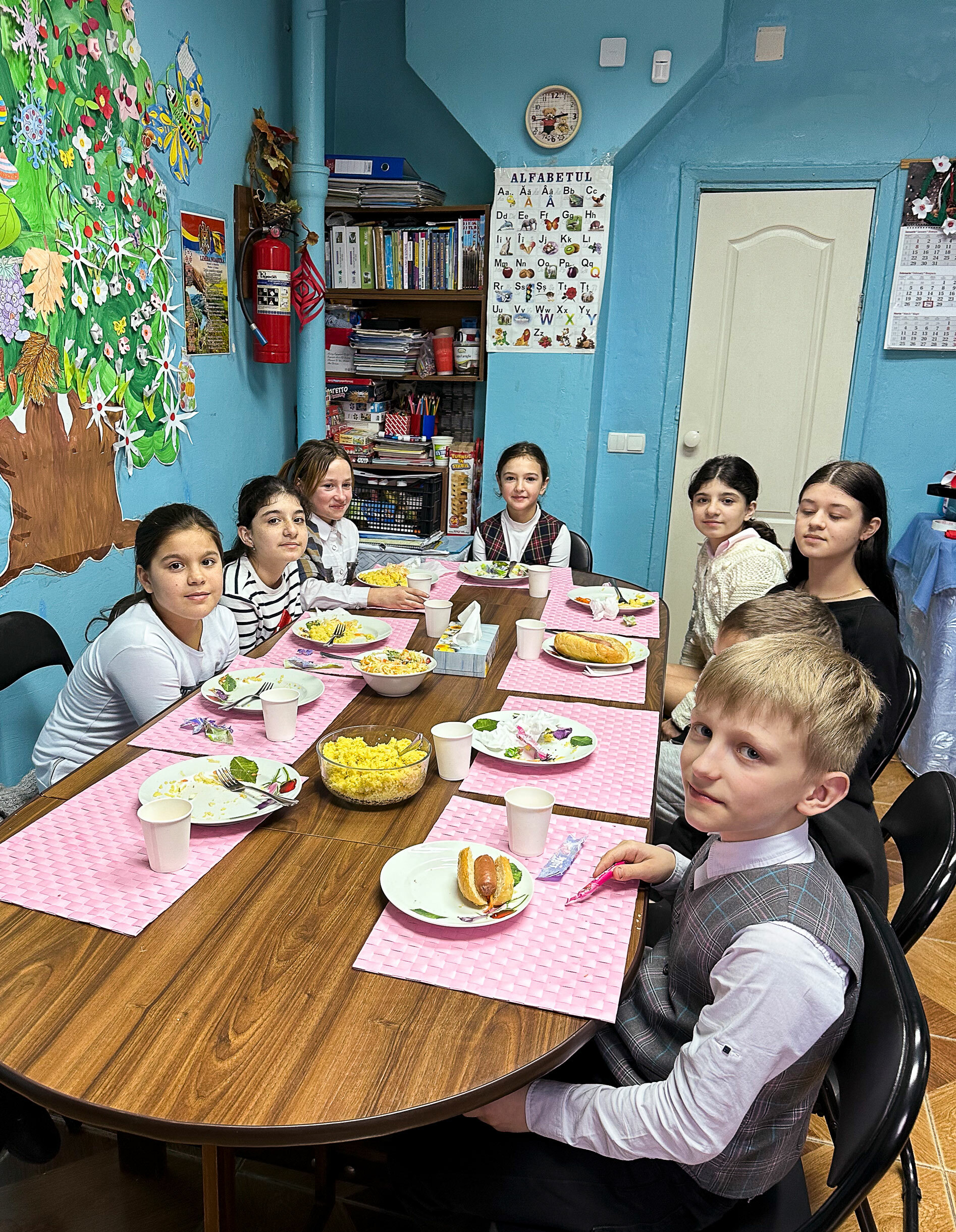 Foto: Åtte barn avbildet rundt et bord som er dekke med tallerkener med mat på.