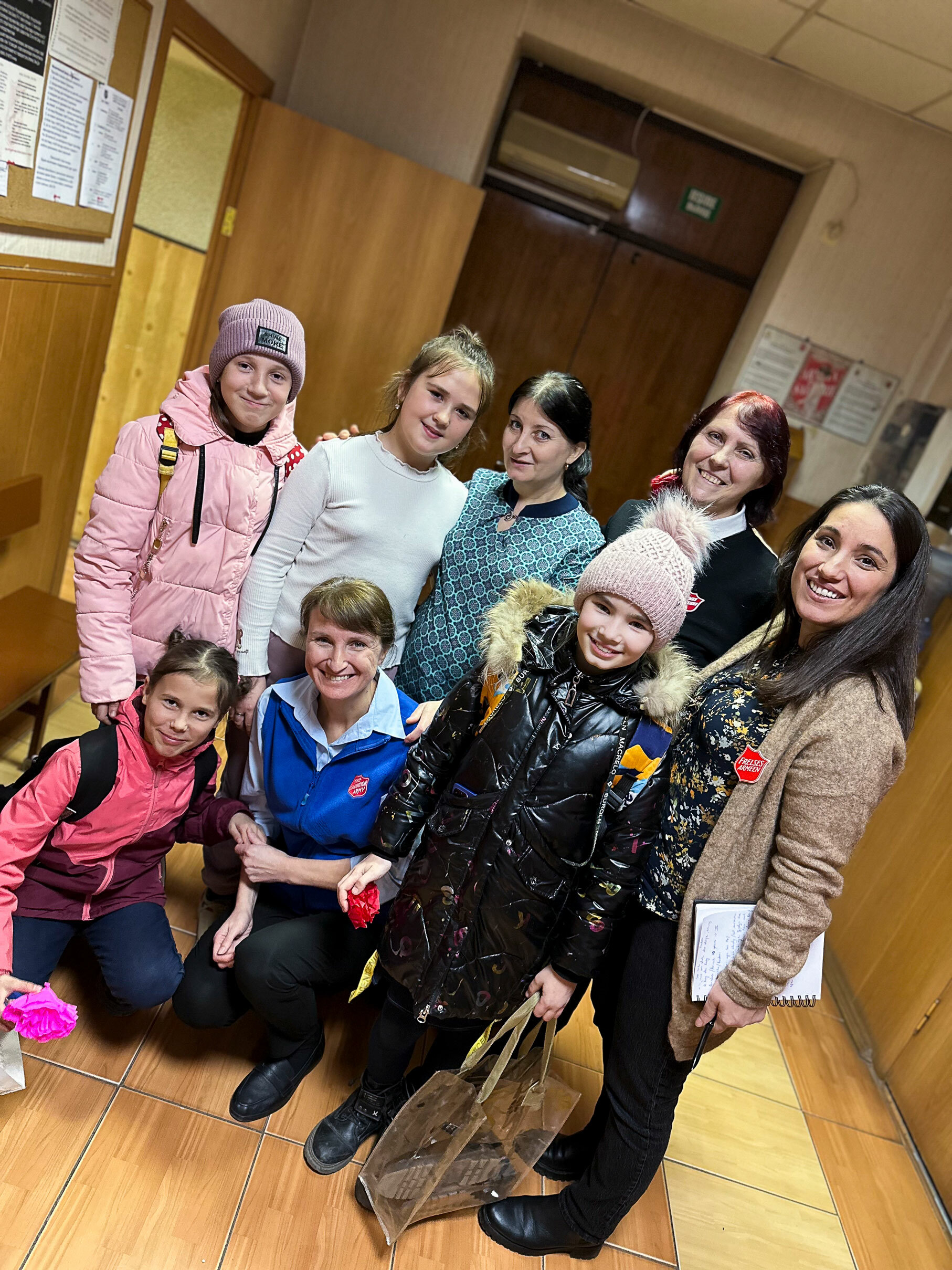 Foto: Fire voksne fra Frelsesarmeen sammen med fire barn som akkurat har kommet inn døra – flere har på seg yttertøy.
