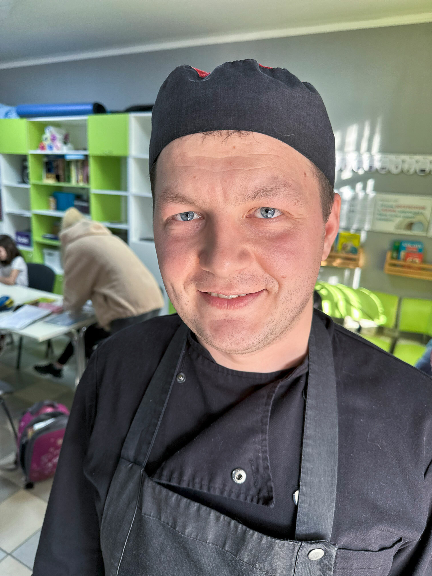 Foto: En ung mann i blå kokkeuniform og forkle smiler til kamera.