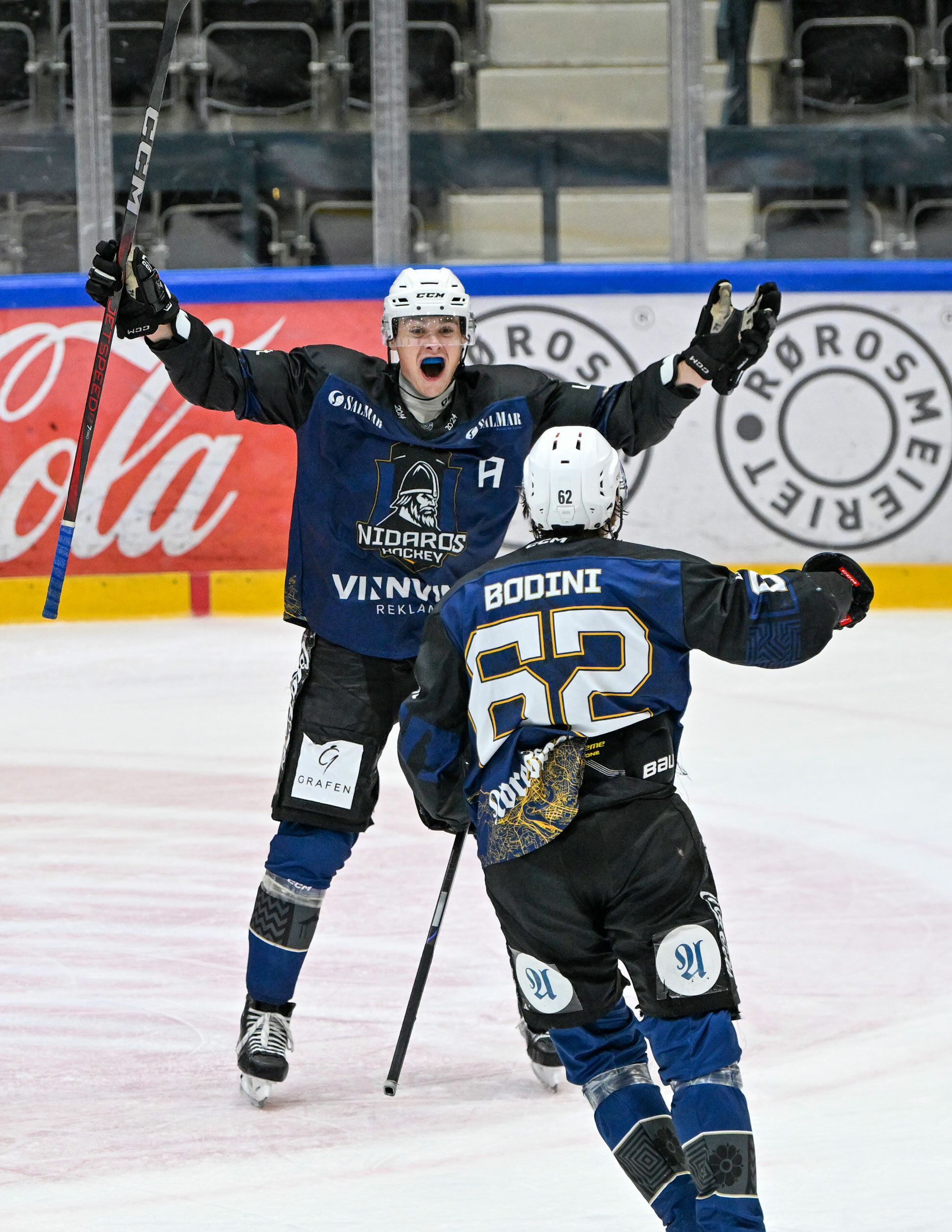 Foto: To menn fra i blå drakter og hvite hjelmer jubler på isen.