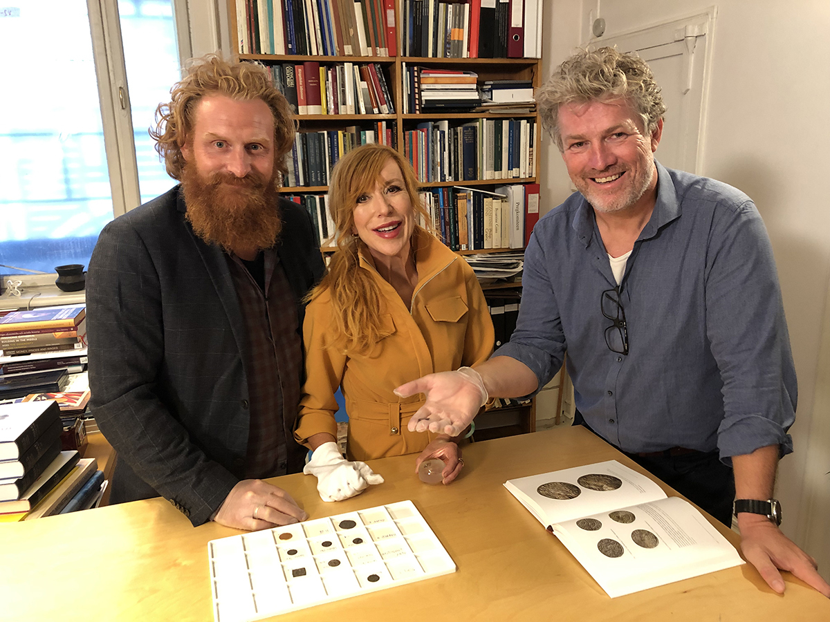 Tre personer står ved et bord og ser inn i kamera