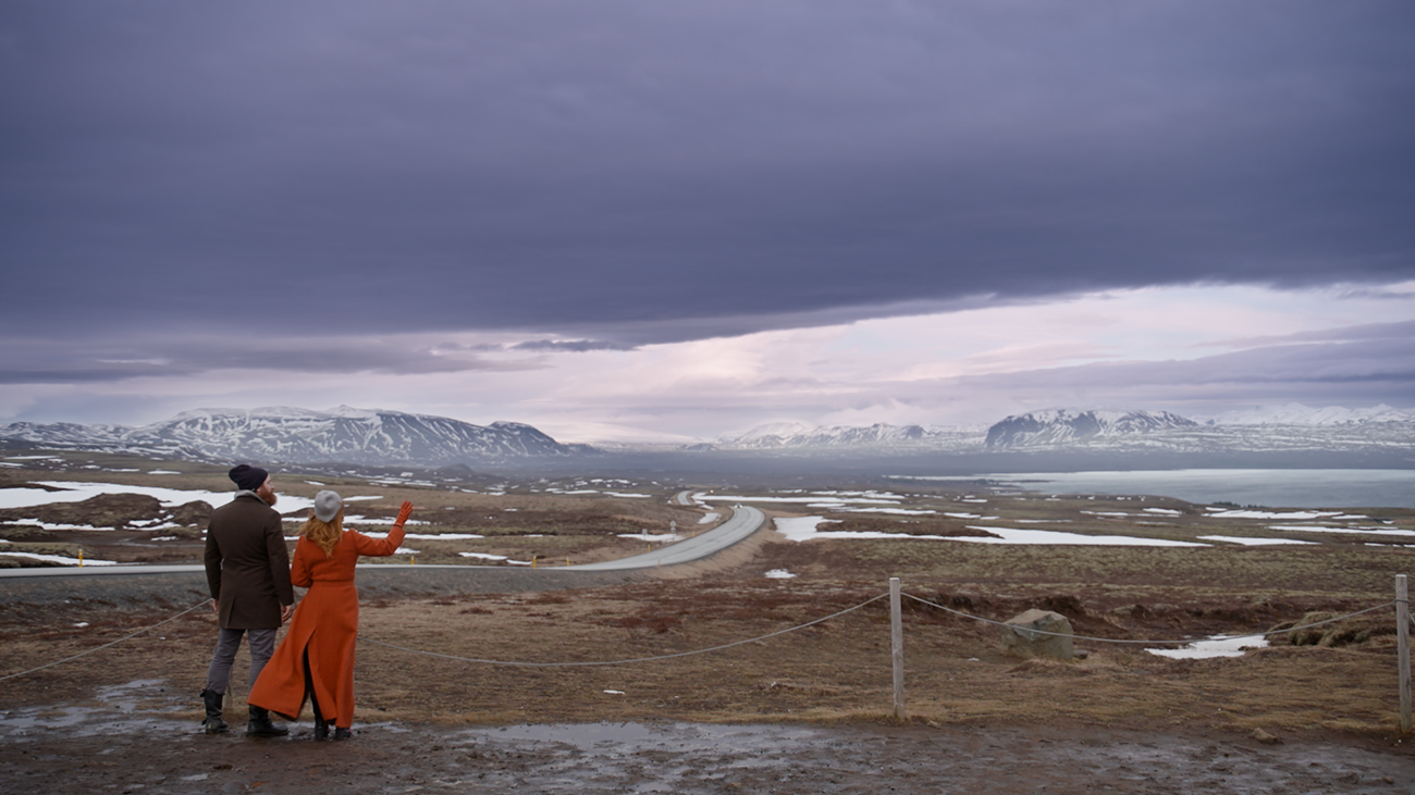 To personer står med ryggen til og skuer utover åpent landskap
