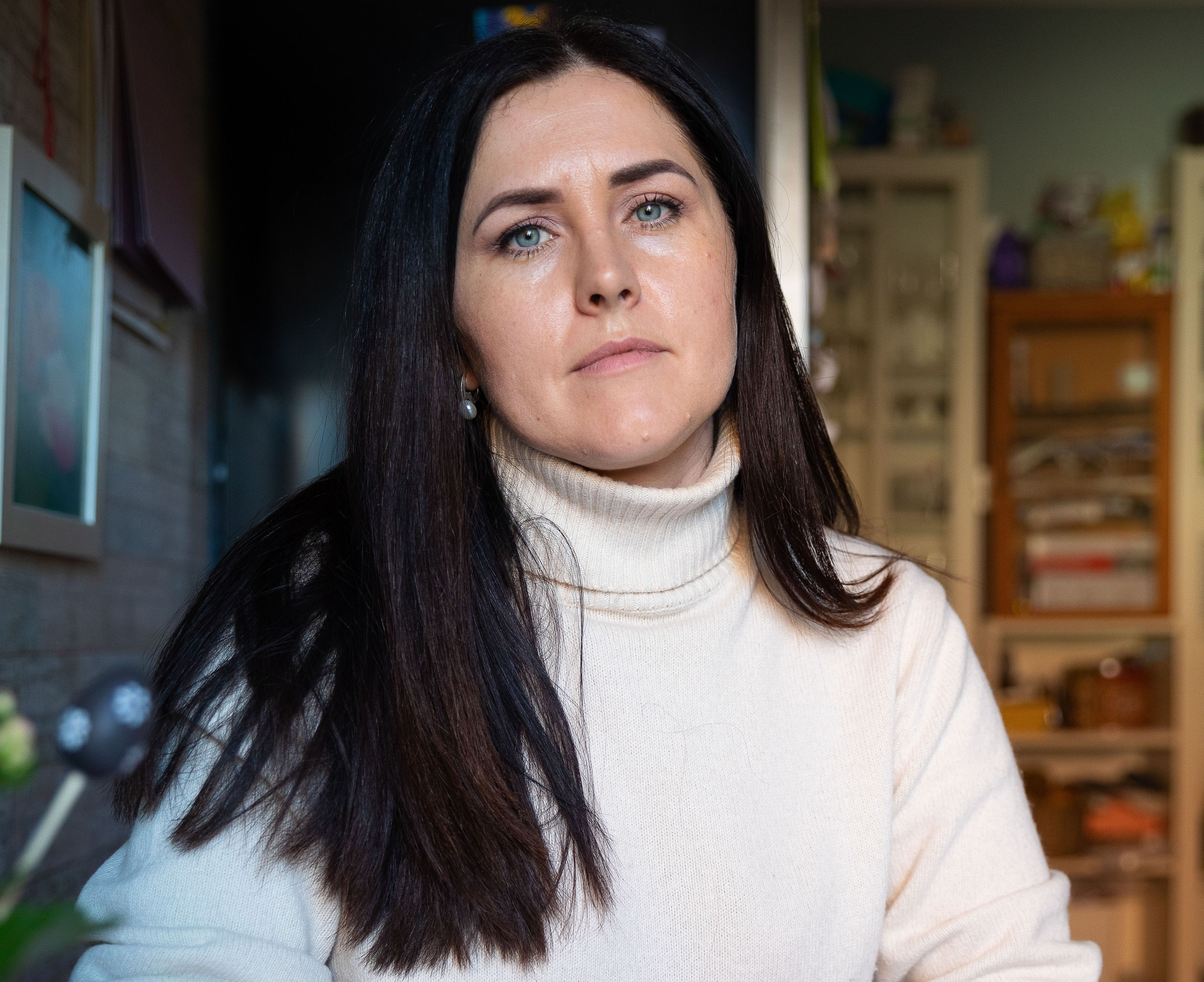 Ung kvinne med mørt hår og høyhalset, hvit genser.