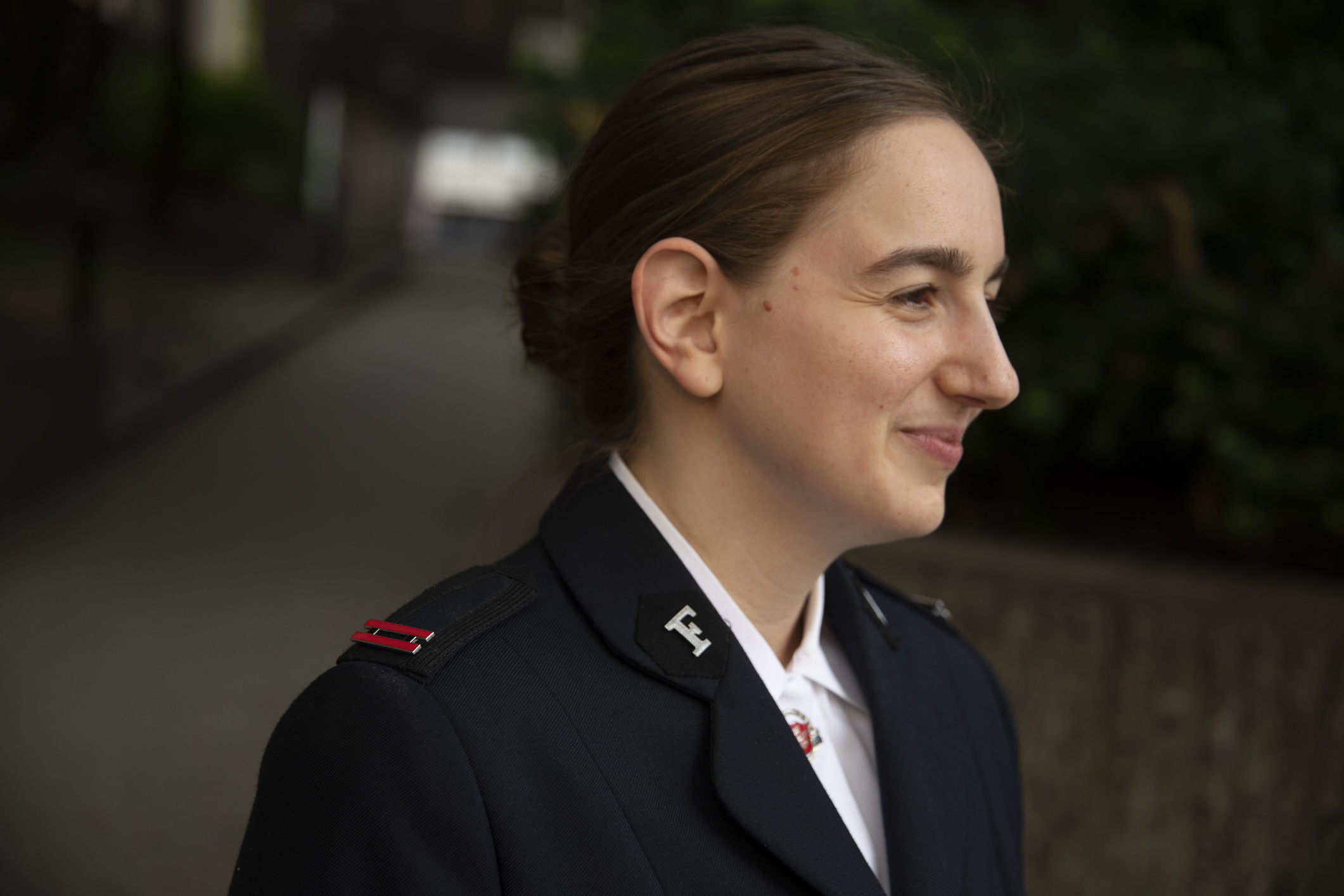 Uniformskledd kvinne i profil. Nærbilde av de røde klaffene på jakka.