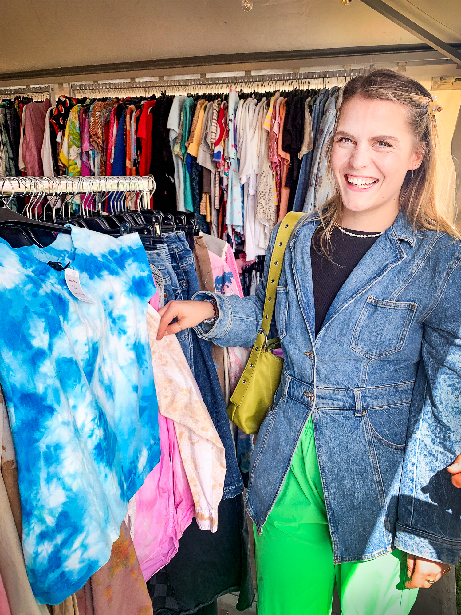 Smilende kvinne peker mot en T-skjorte med batikkmønster.
