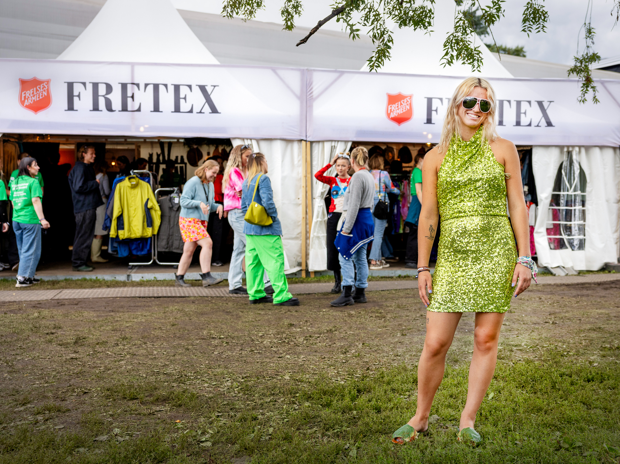 Kvinne i kort, grønn paljettkjole og solbriller.