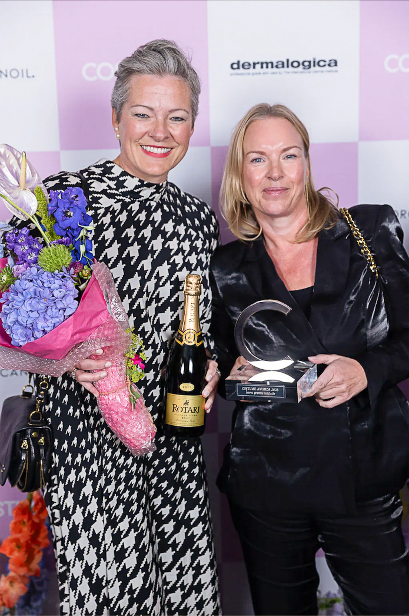 To kvinner holder blomster og en pris de er blitt tildelt.