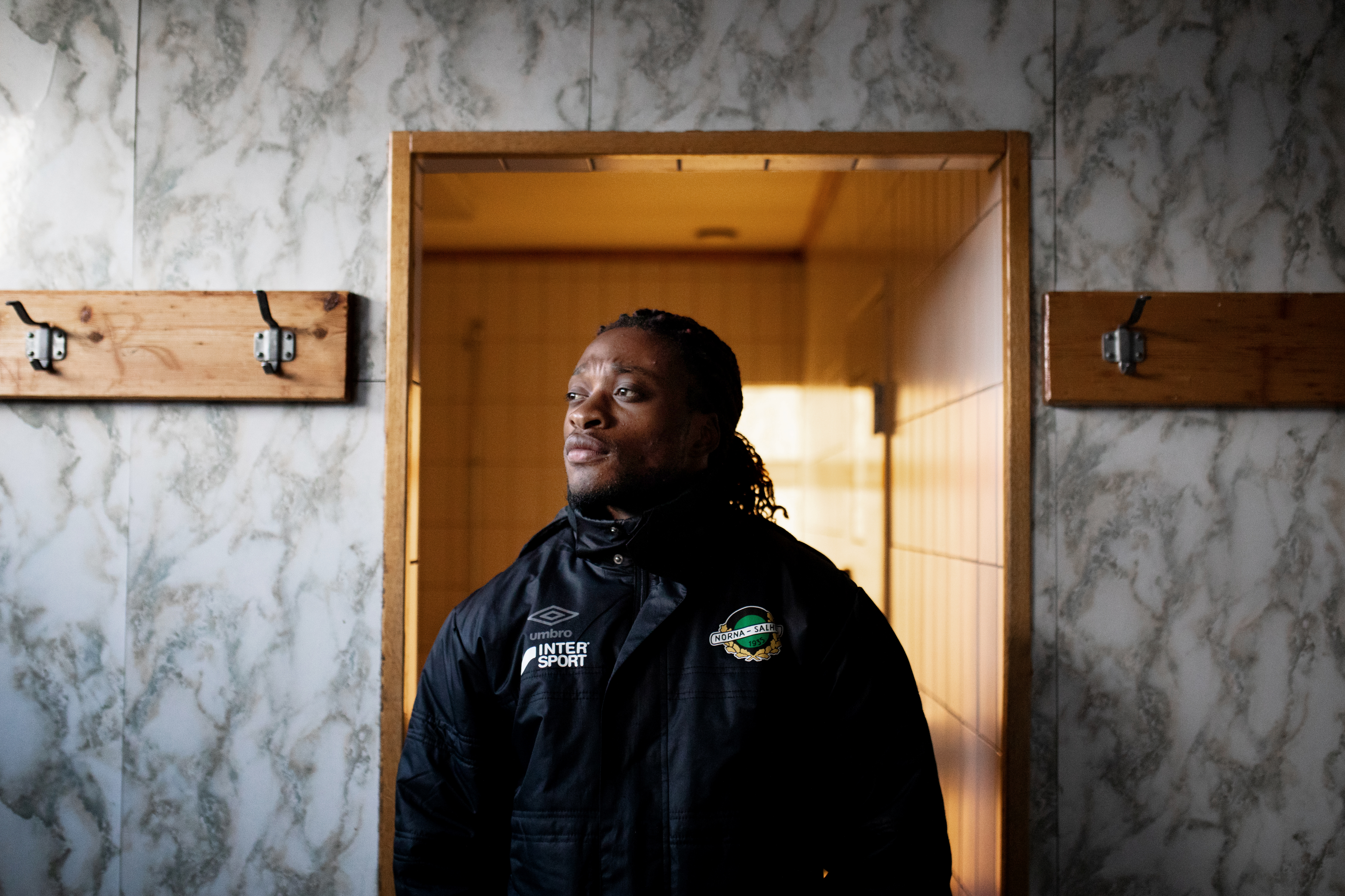 Salum Ageze Kashafali står i svart jakke i en garderobe og ser mot siden.