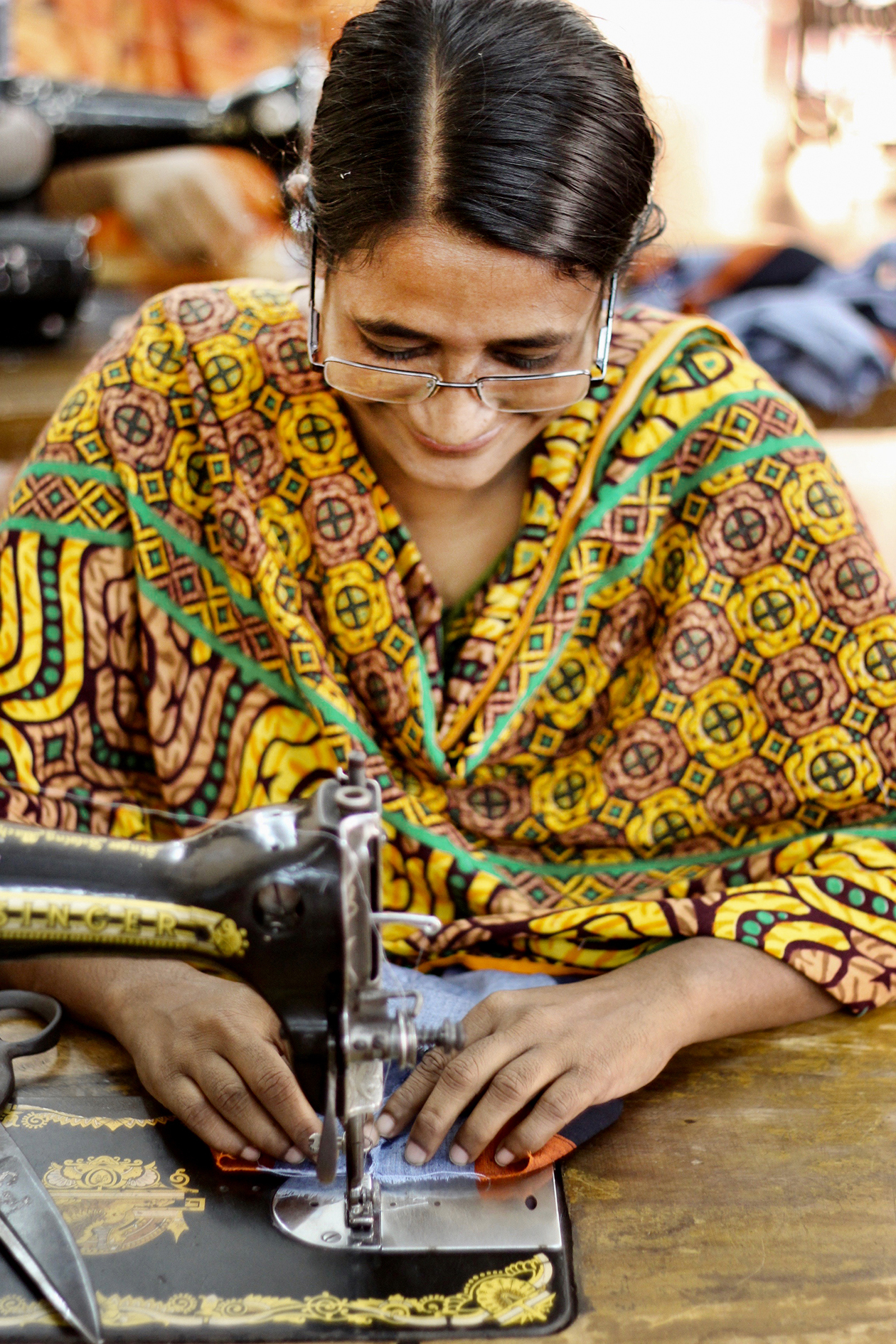 En asiatisk kvinne sitter ved symaskinen og jobber