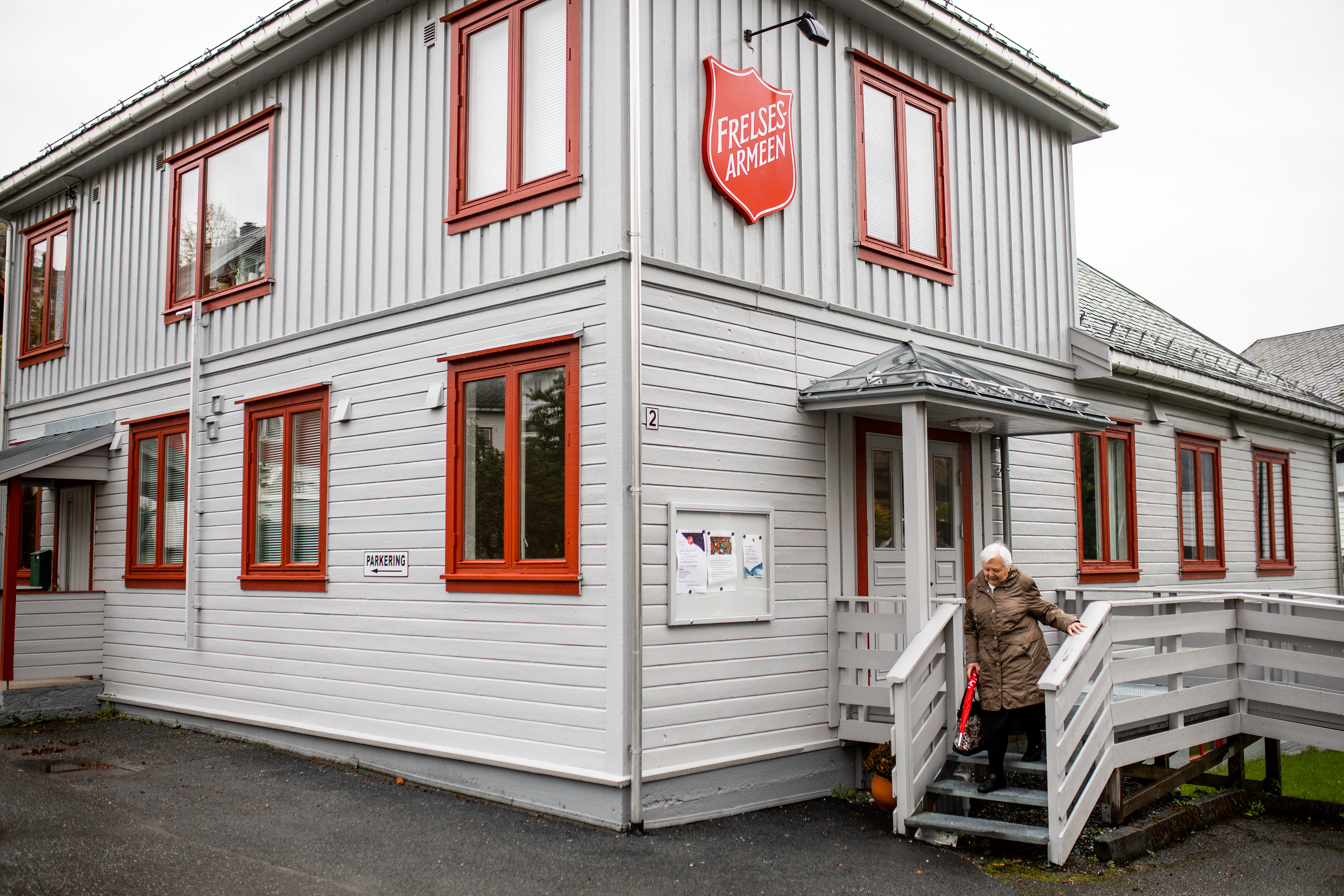 Bildet er tatt på avstand og viser Petra på vei ned en trapp på utsiden av et hvitt trebygg med frelsesarme-skjold.