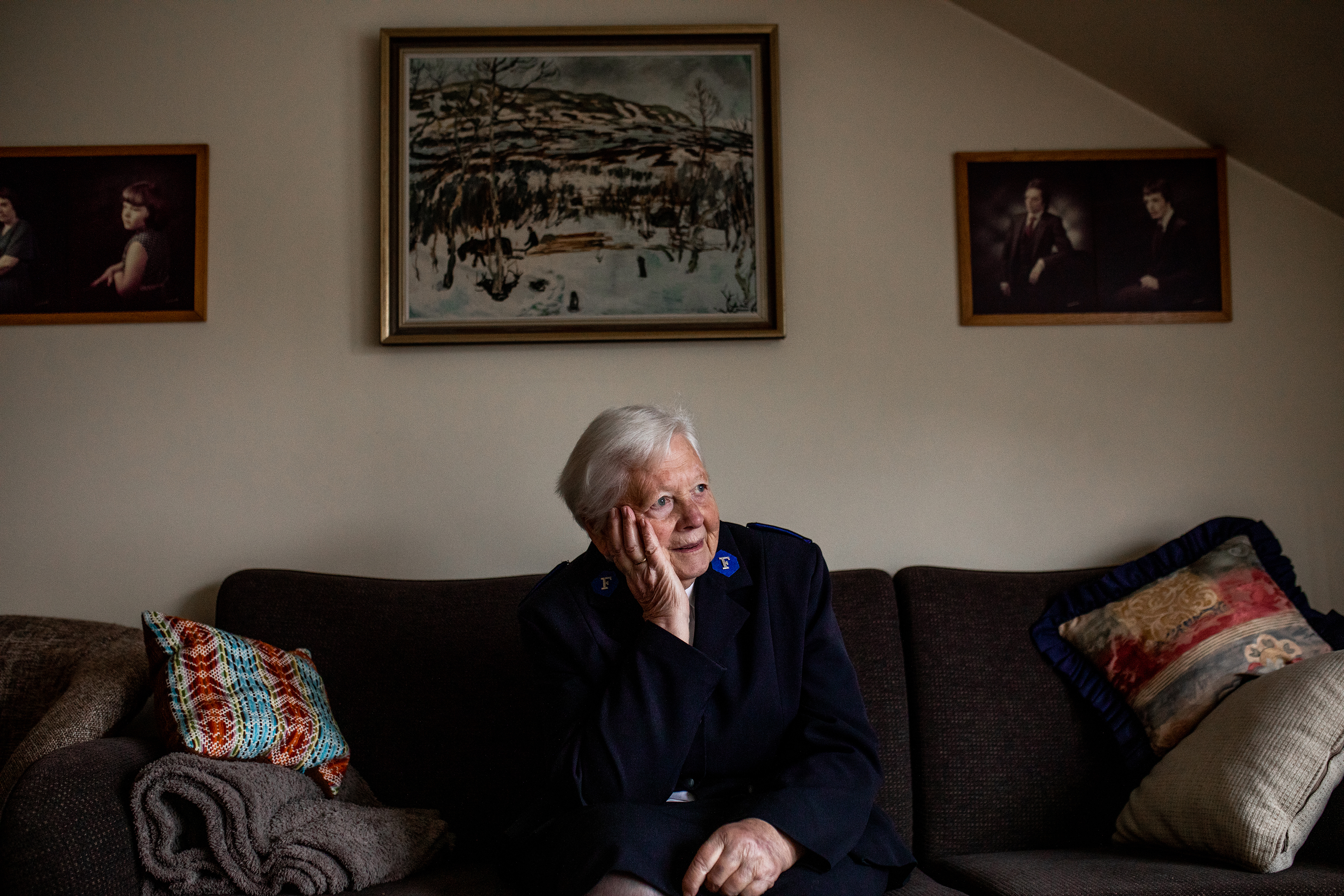 Bildet viser Petra som sitter på en sofa og ser ut mot siden. Bak henne er tre bilder.