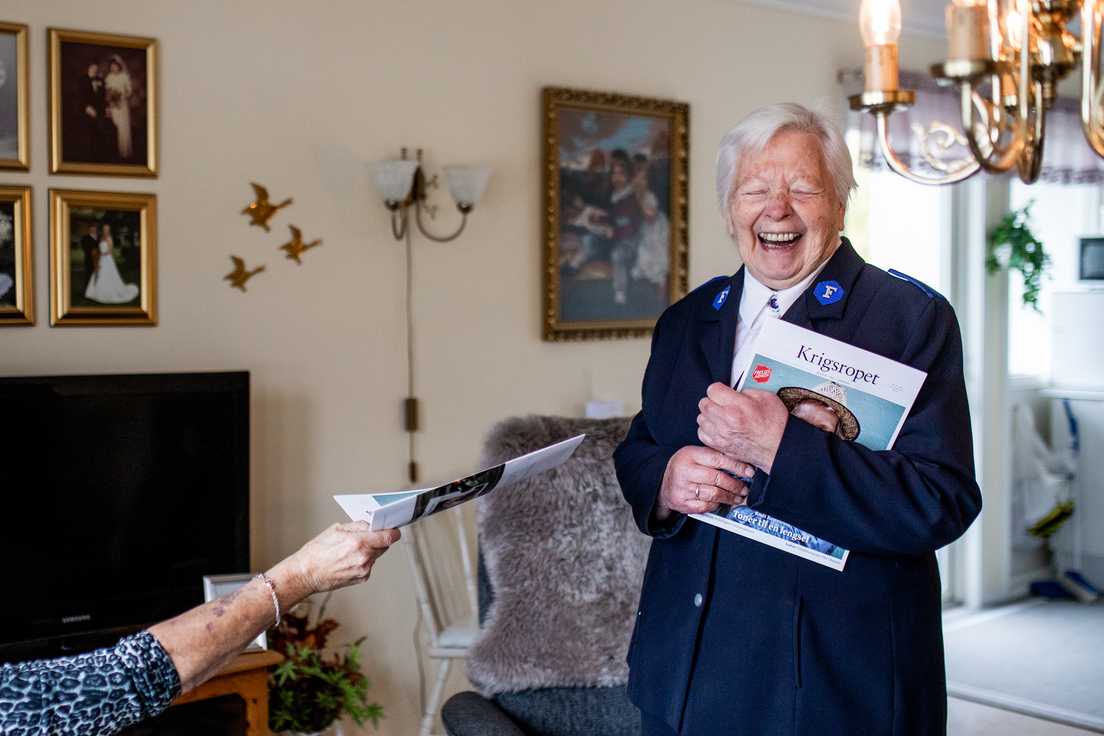 Bildet viser en hånd som akkurat har tatt imot Krigsropet og Petra som holder en bunke blader og ler.