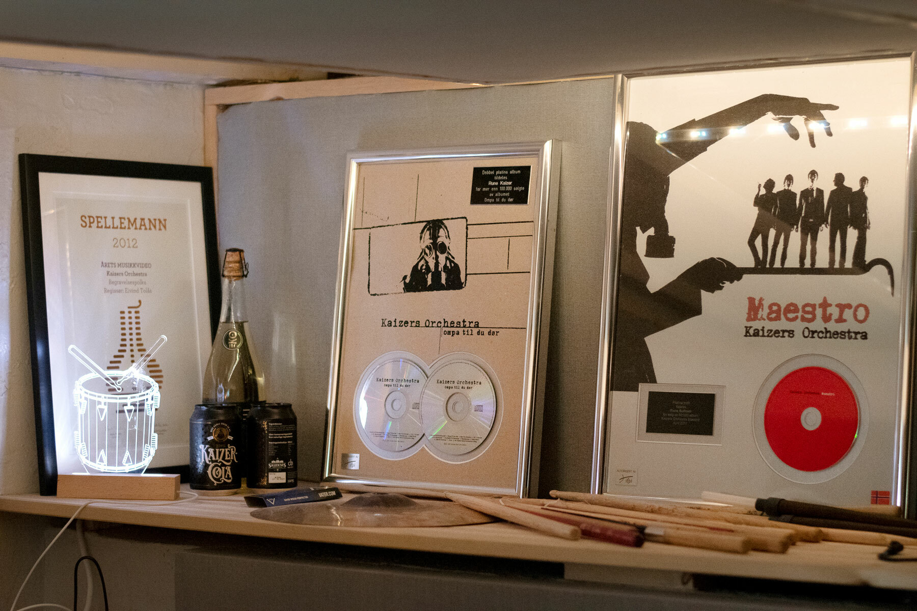 Foto: Det første bildet viser priser på en hylle etter hverandre. Det andre bildet viser to nye priser, deriblant en Spellemann.