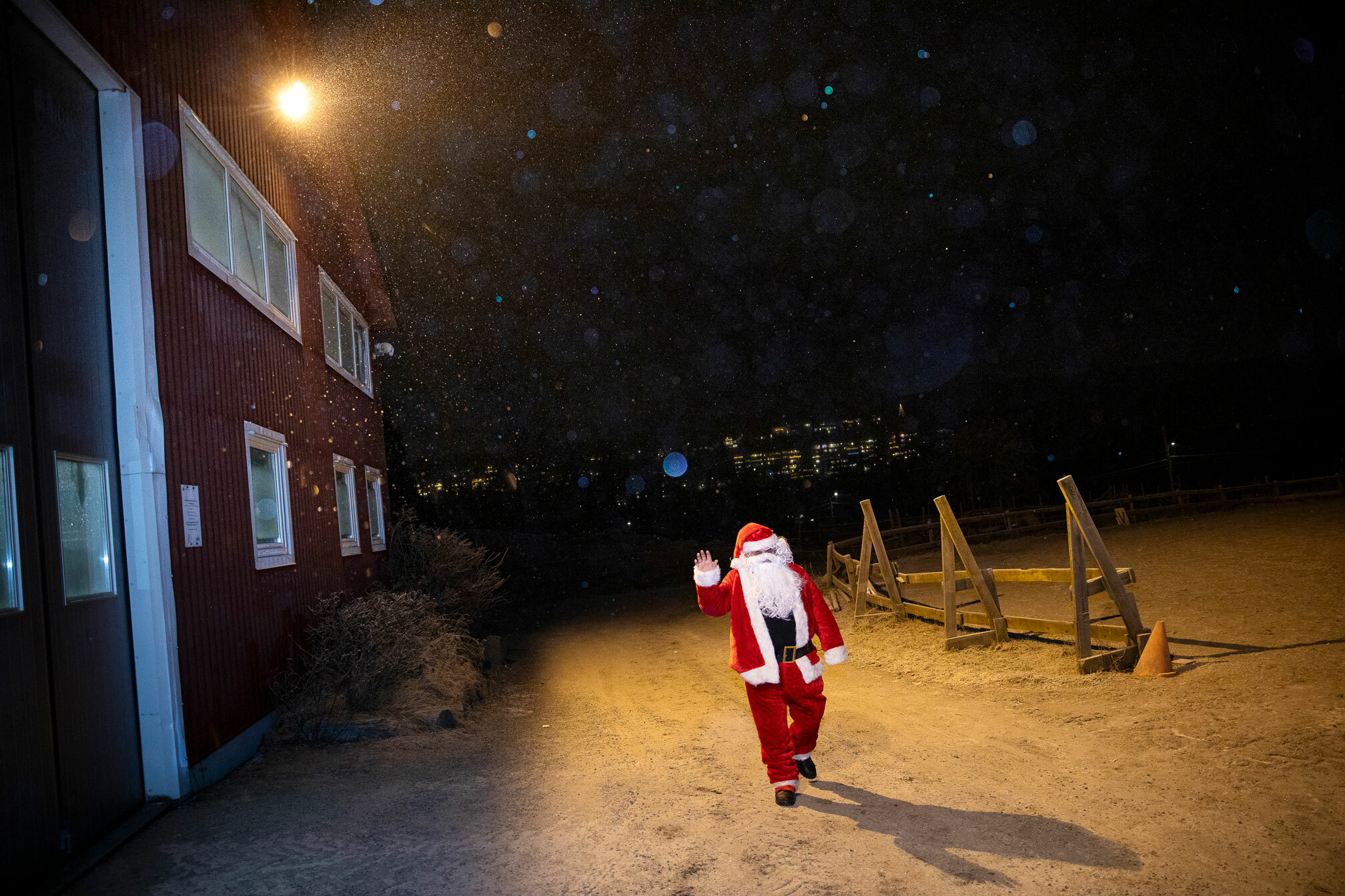 Foto: Mann i nissedrakt kommer gående langs et rødt hus i snøen.
