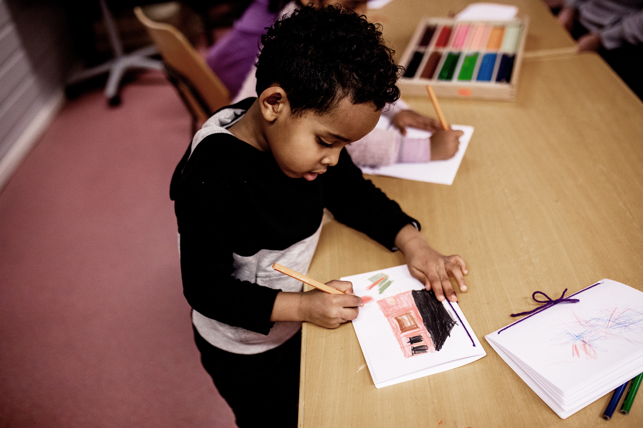 Det flrste bildet viser en gutt som tegner et hus. Det andre bildet viser en smilende jente som sitter på toppen av en grønn plastsklie.