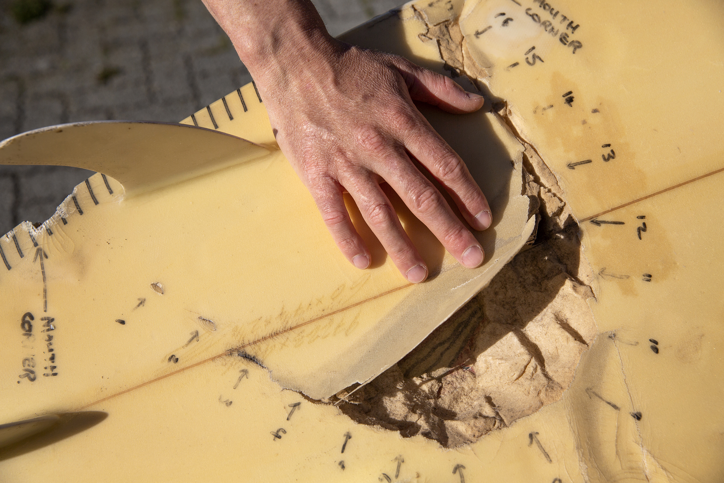 Til venstre: Shannon står med surfebrett under armen. Til høyre: Nærbilde av surfebrettet der man ser bittet til den store hvithaien som angrep ham.