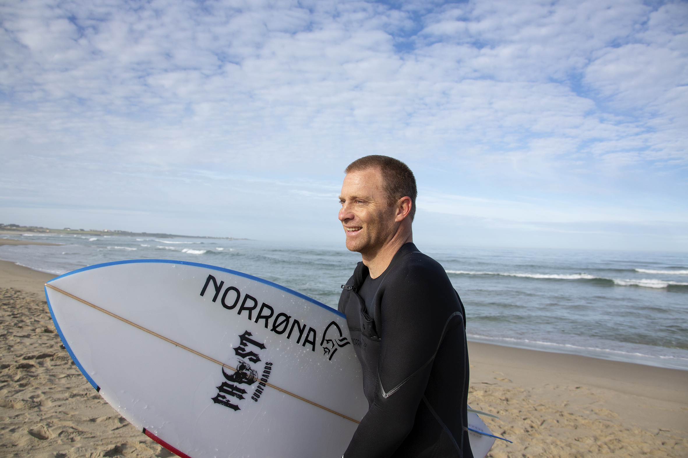 Shannon i profil med surfebrettet under armen.