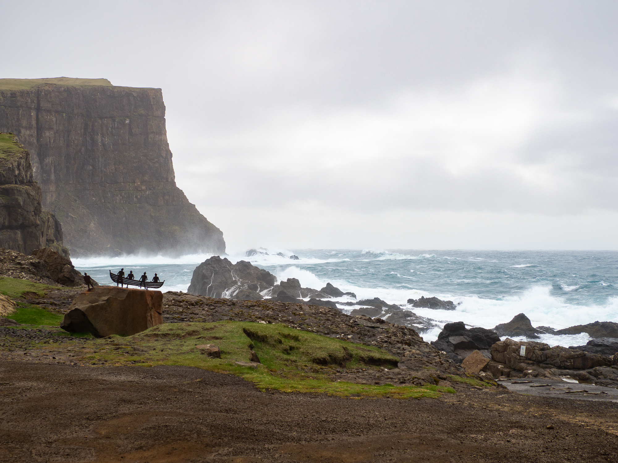 Golde flater med mye stein, klipper som stuper ned i et hav med hvite skumtopper. Det blåser hardt.