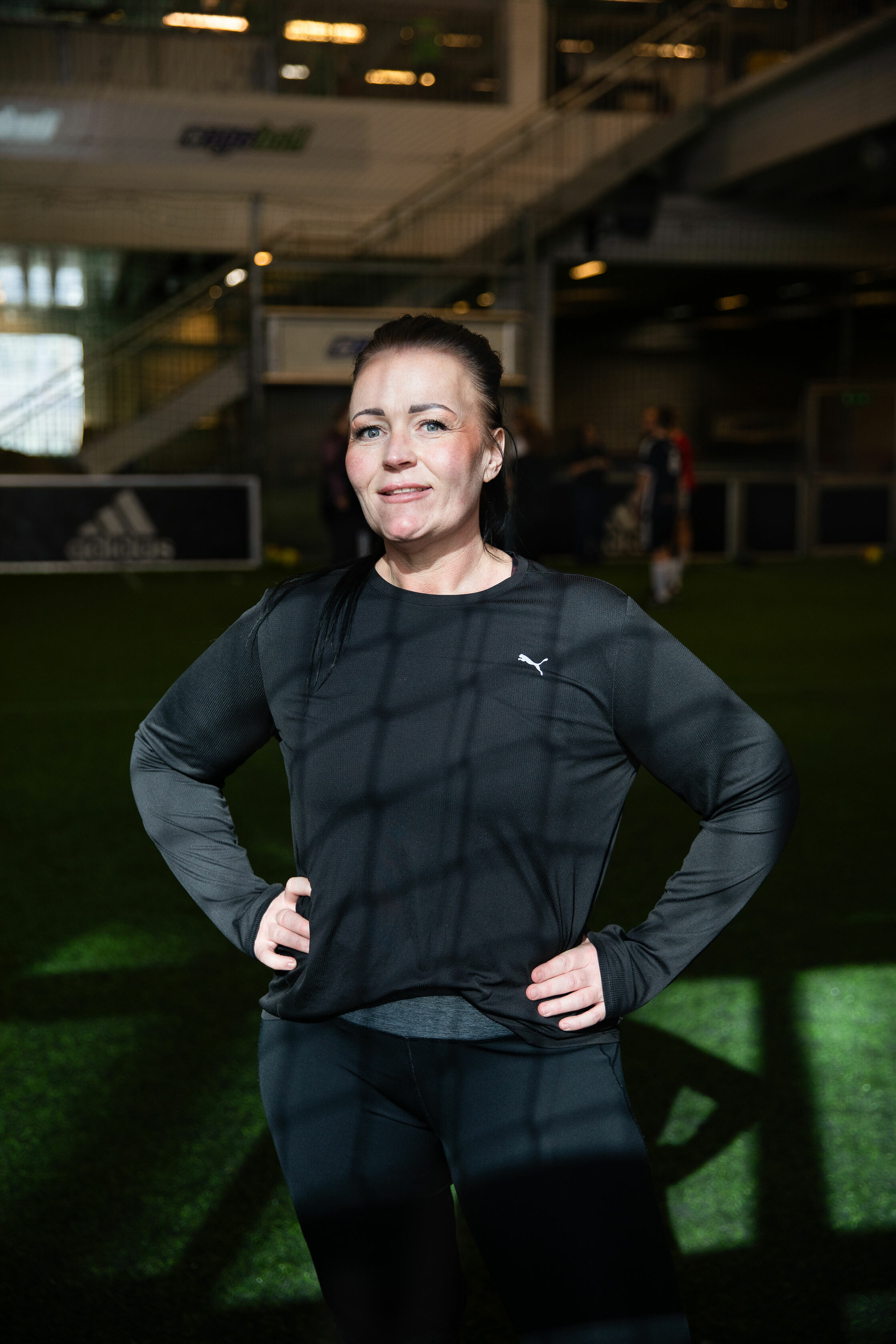 Foto: Kvinne i sorte treningsklær sees gjennom skyggen fra nettingen i fotballmålet.