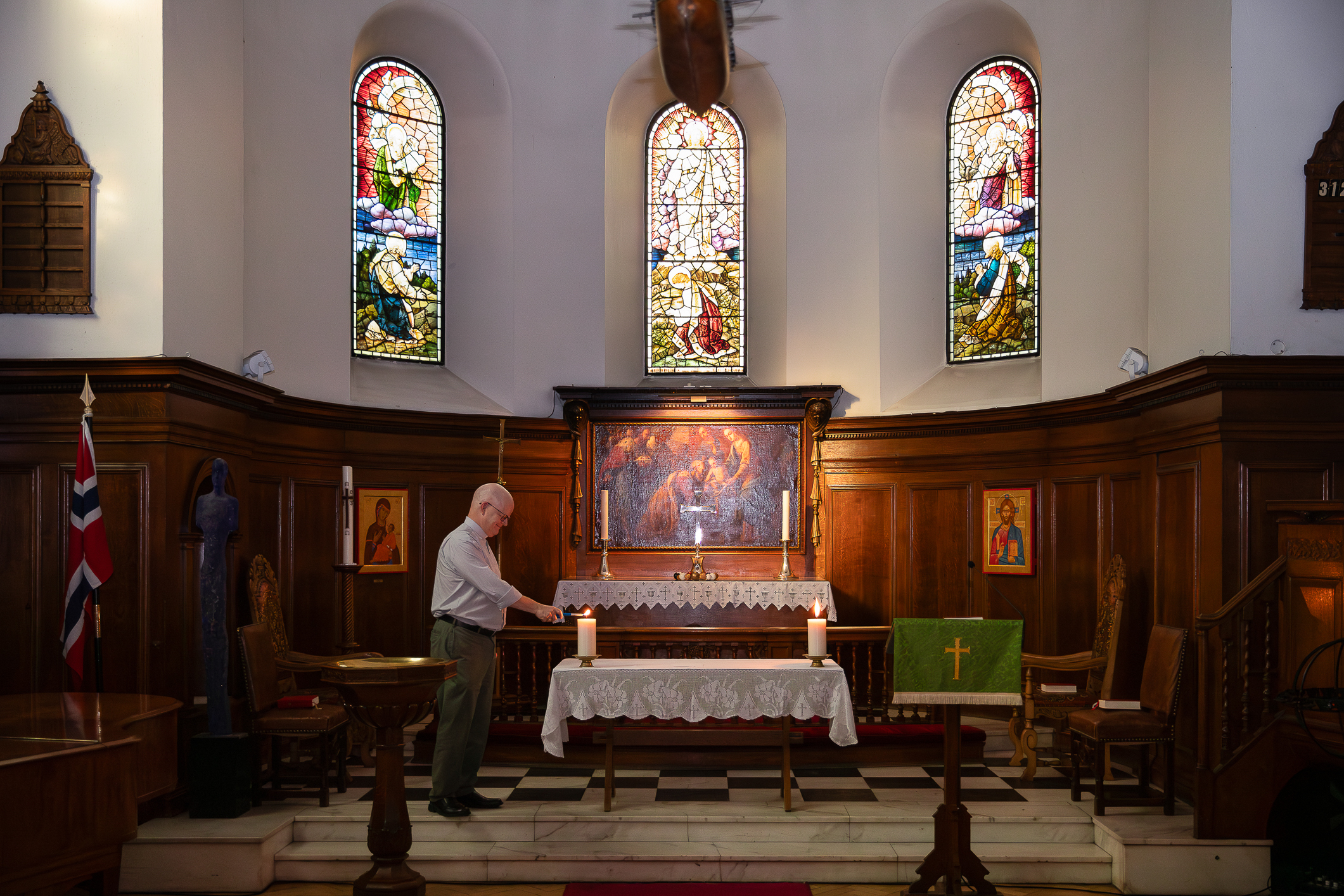 Kirkerom der prest tenner lys på et bord med blondeduk.