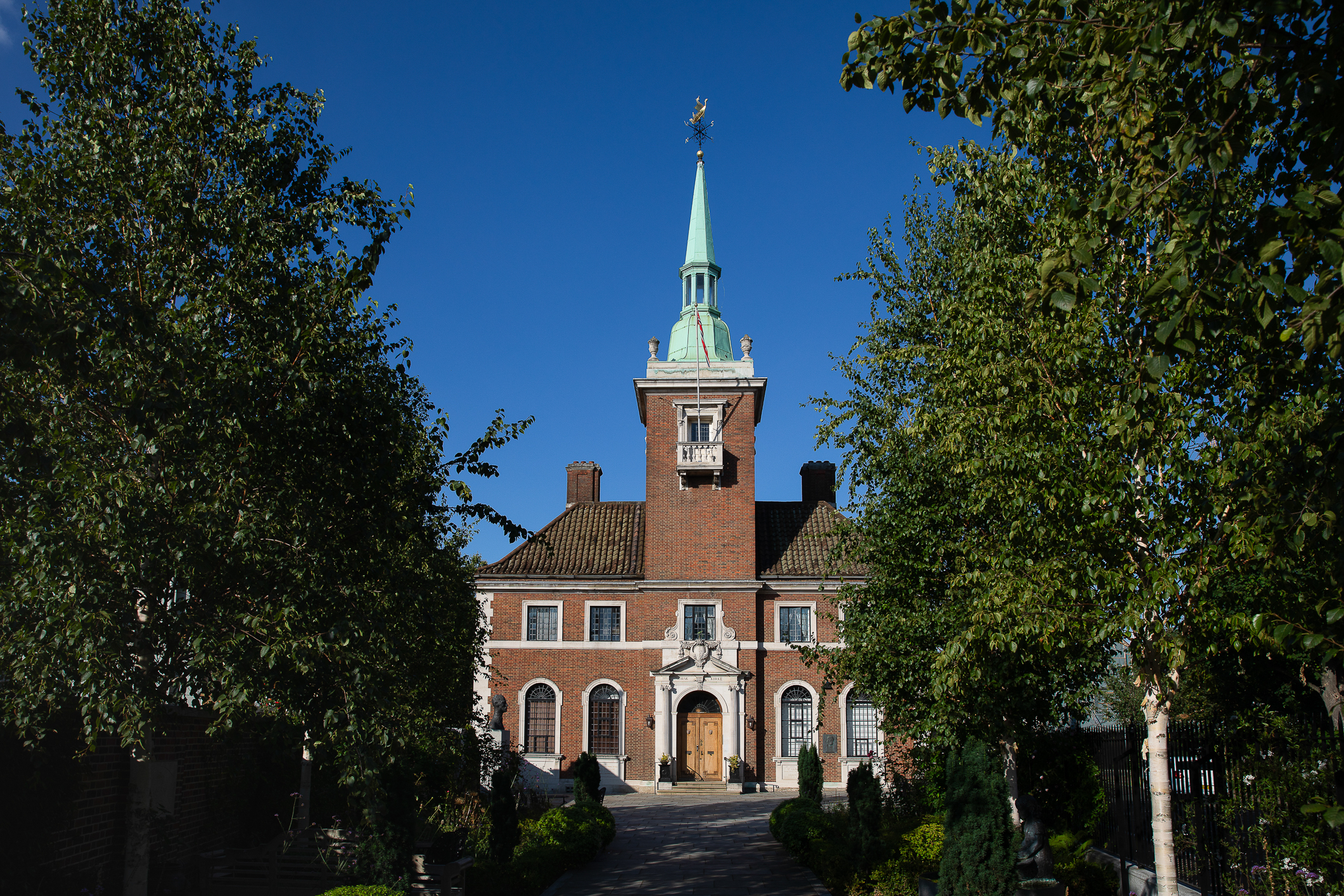 Kirke med spir sett fra et stykke unna. Omringet av grønne trær.
