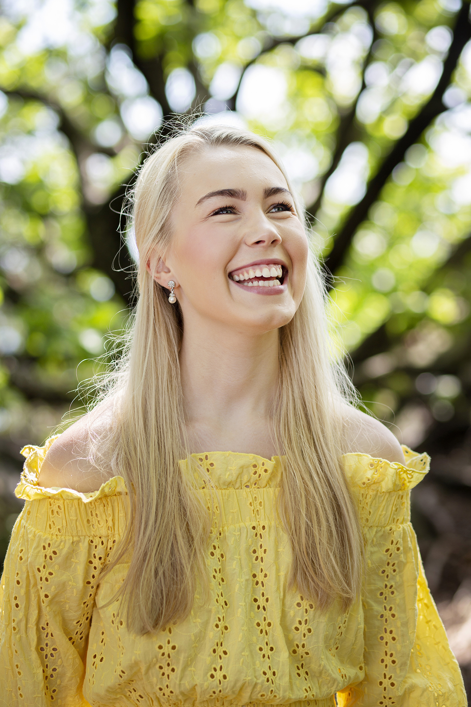 Sophie Fjellvang smiler til kamara, hun har lyst langt hår, blå øyne og en gul topp