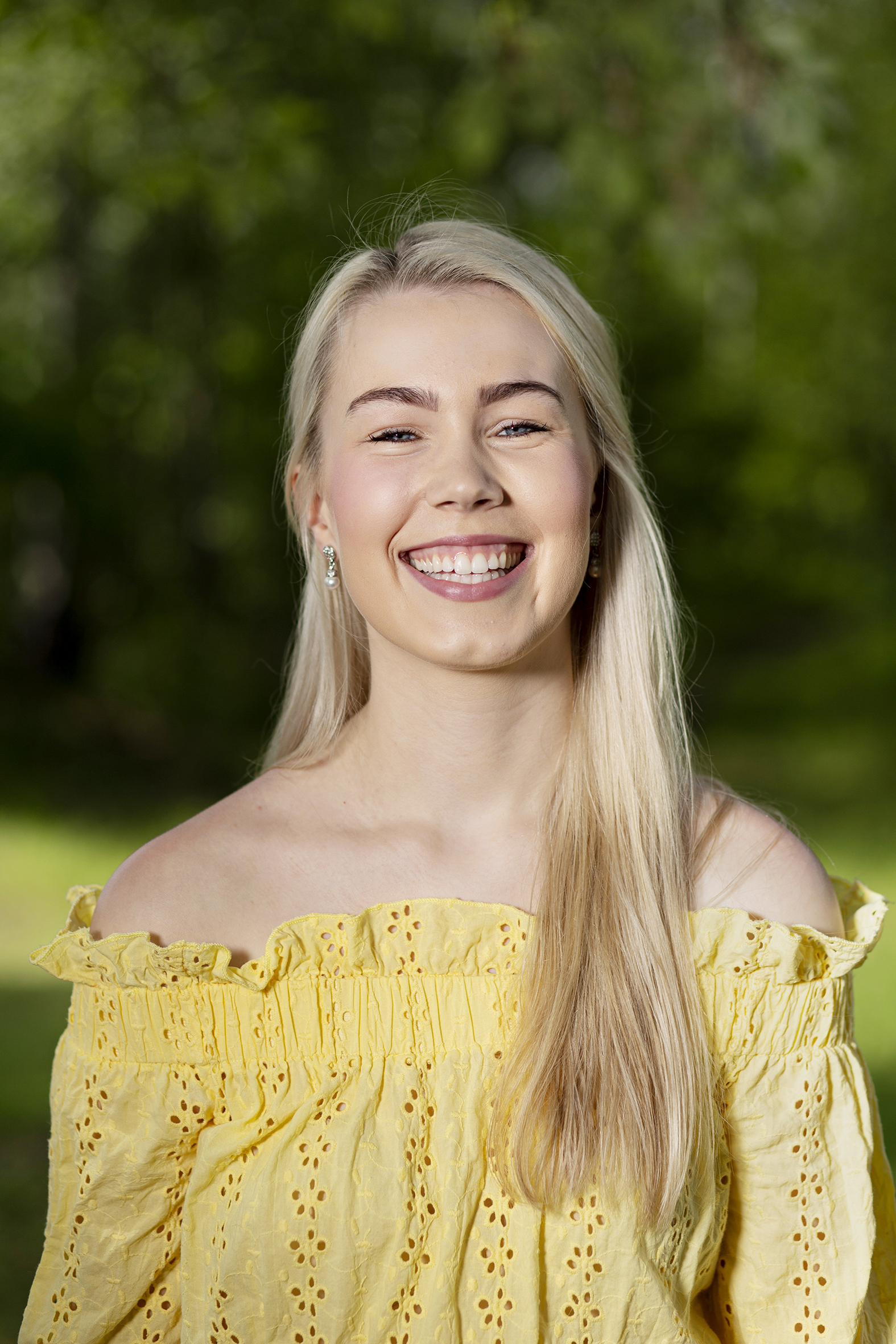 Sophie Fjellvang smiler til kamara, hun har lyst langt hår, blå øyne og en gul topp
