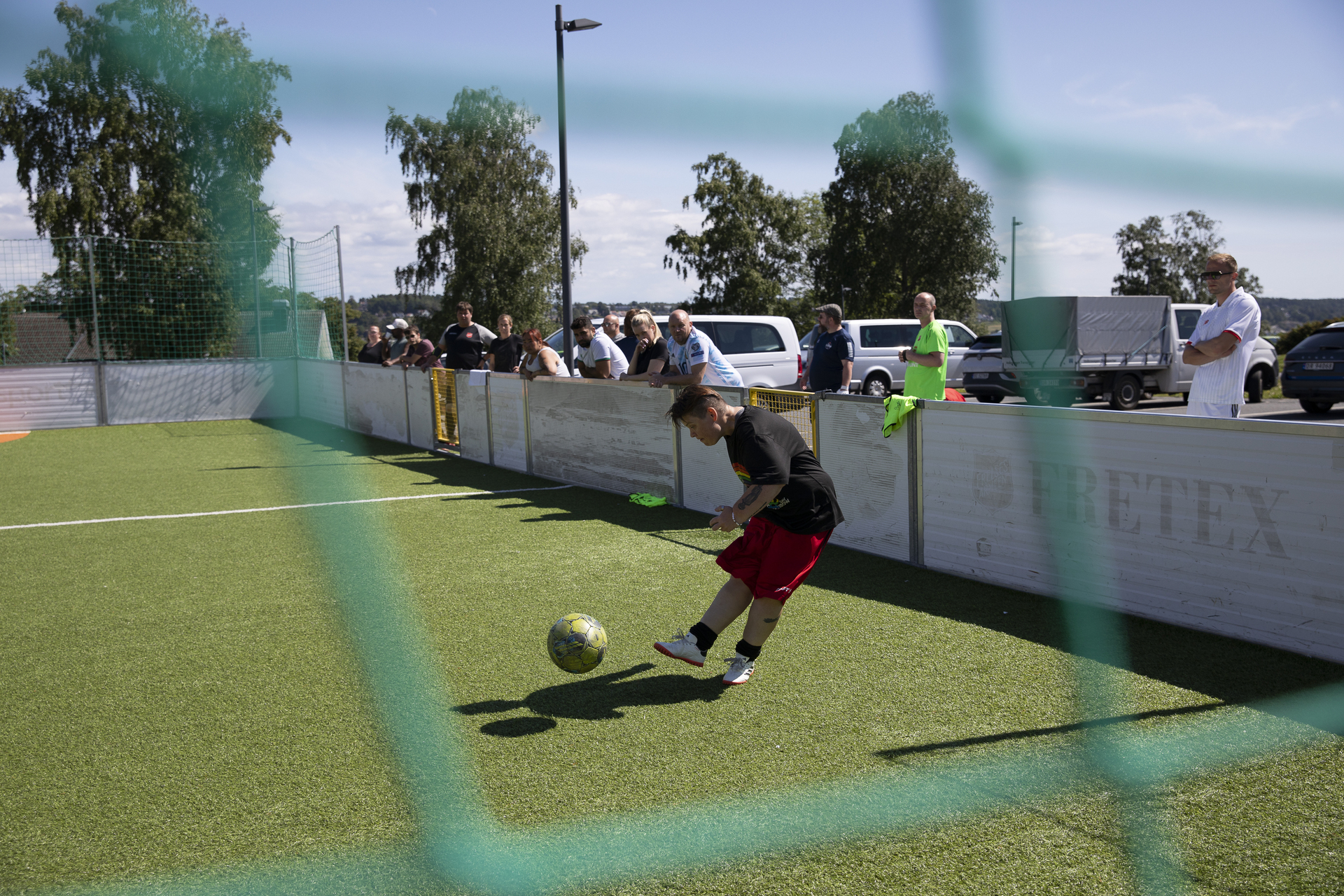 Foto: Kvinne som trikser med en fotball i en ballbinge. Det står en rekke mennesker og ser inn over kanten til bingen.