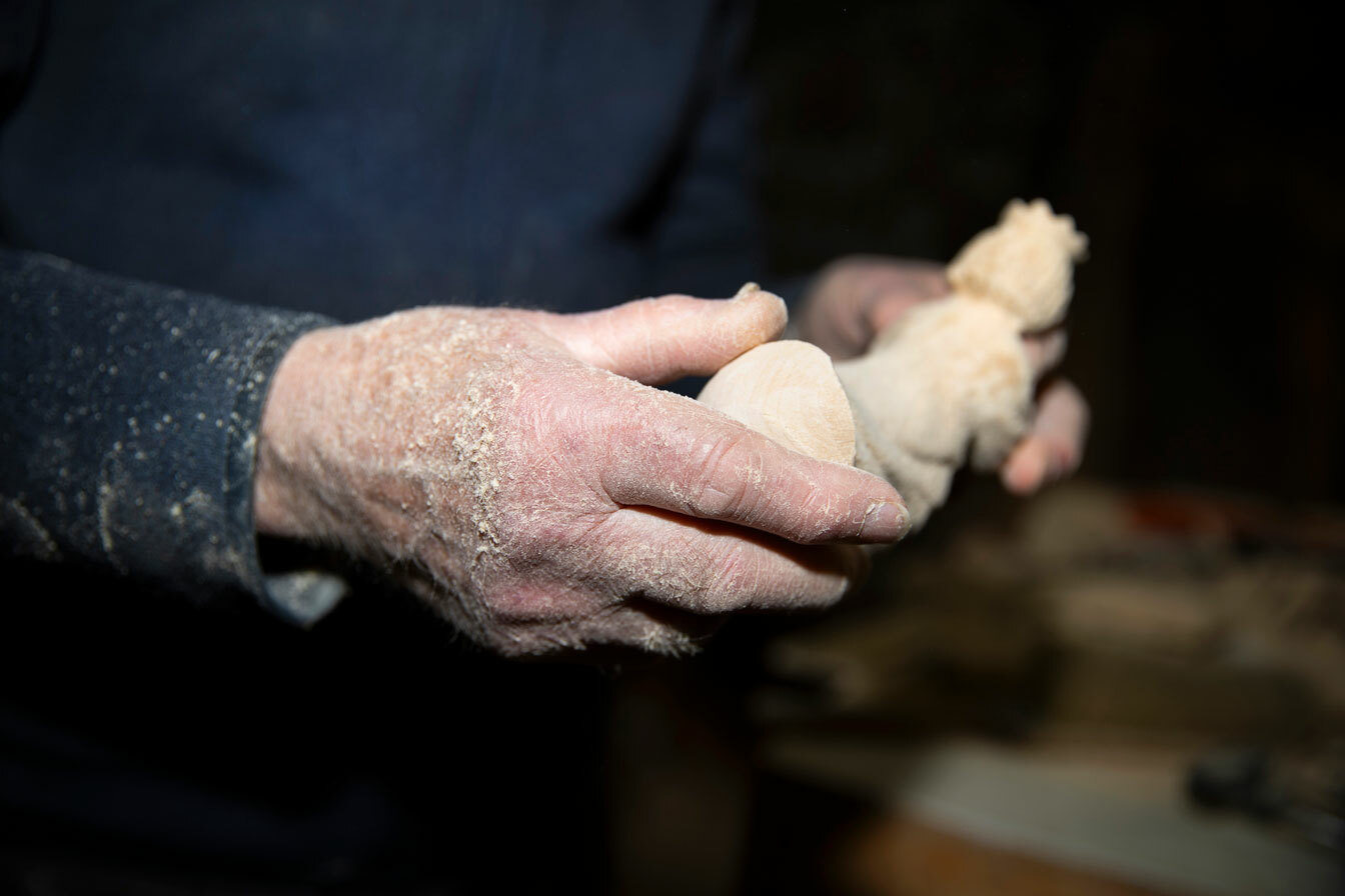 Foto: Støvete mannshender til en mann holder en figur i tre.