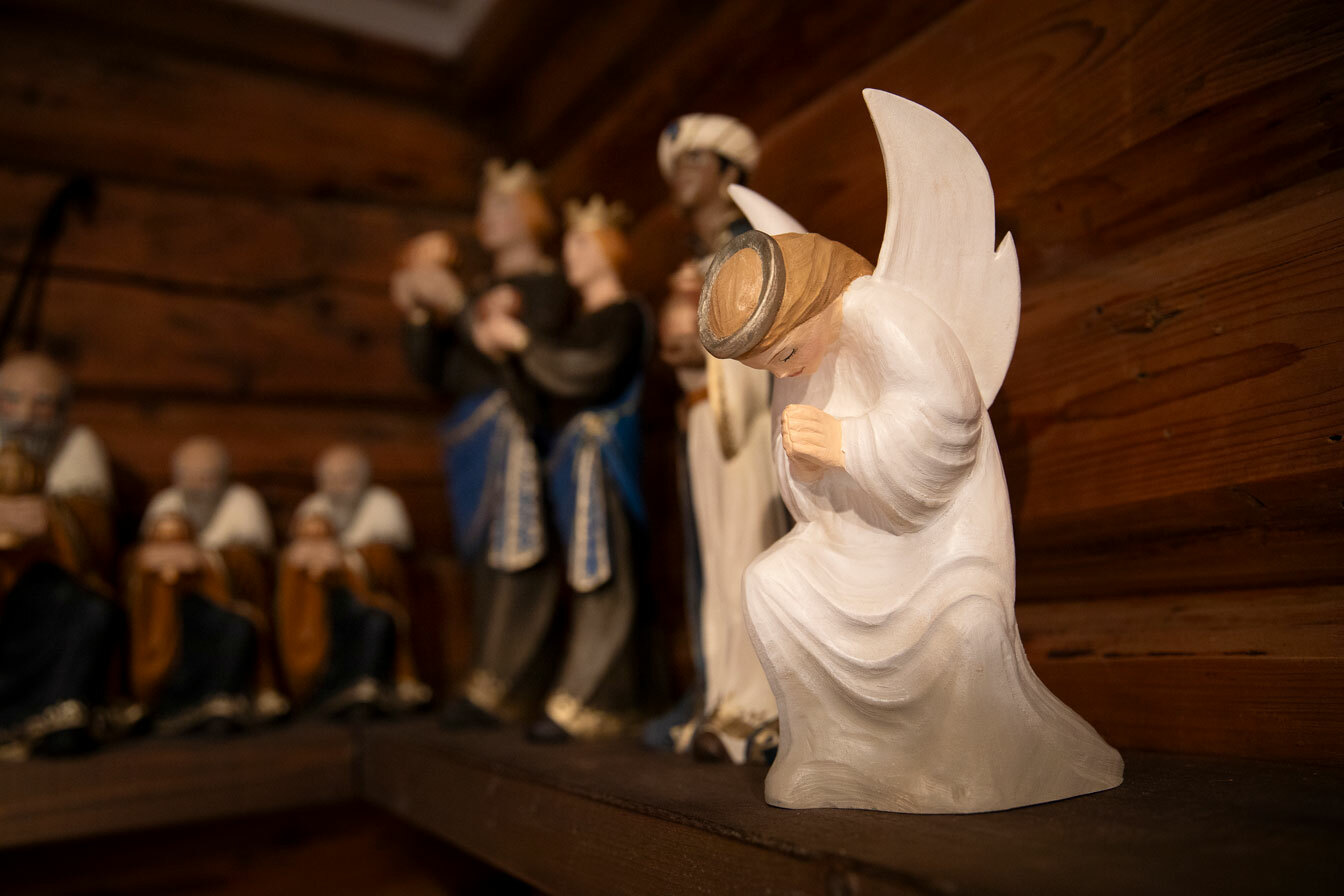 Foto: En rekke med trefigurer, bestående av en hvit engel som bøyer hodet og knær. Videre står det flere vise menn med gaver.