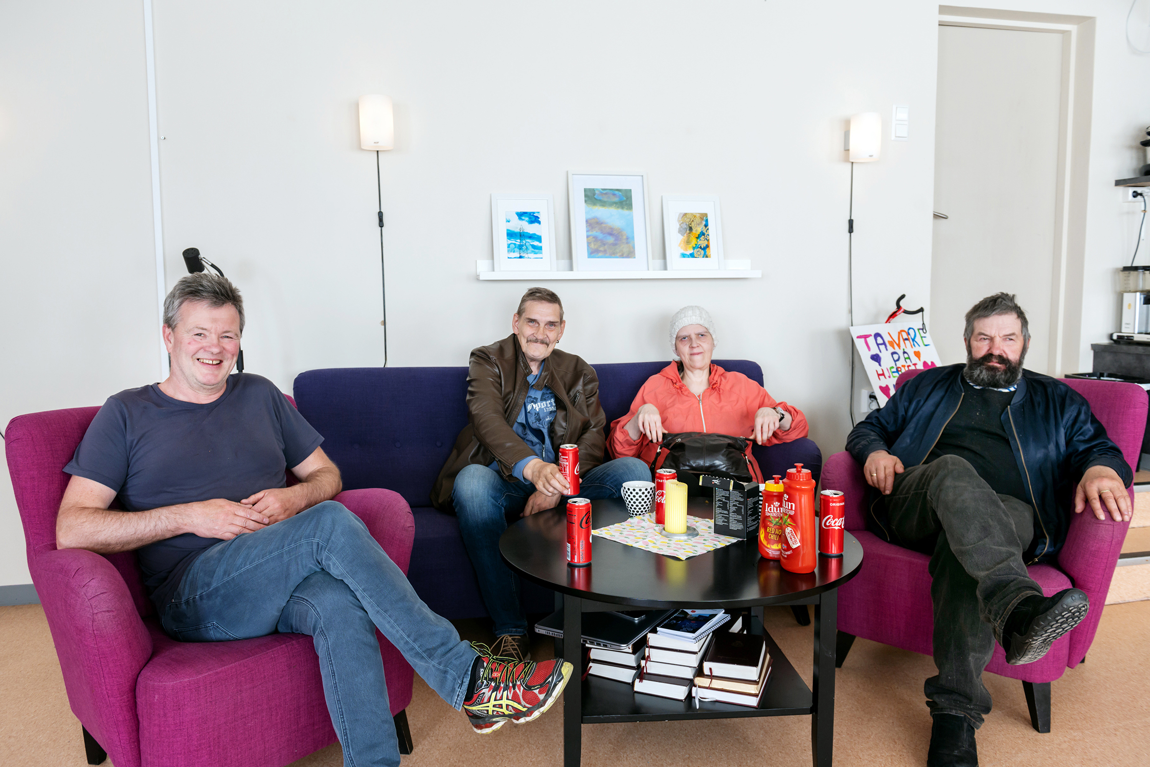 En blid gjeng som sitter i hver sin fargerike stol og sofa inne på Stedet.