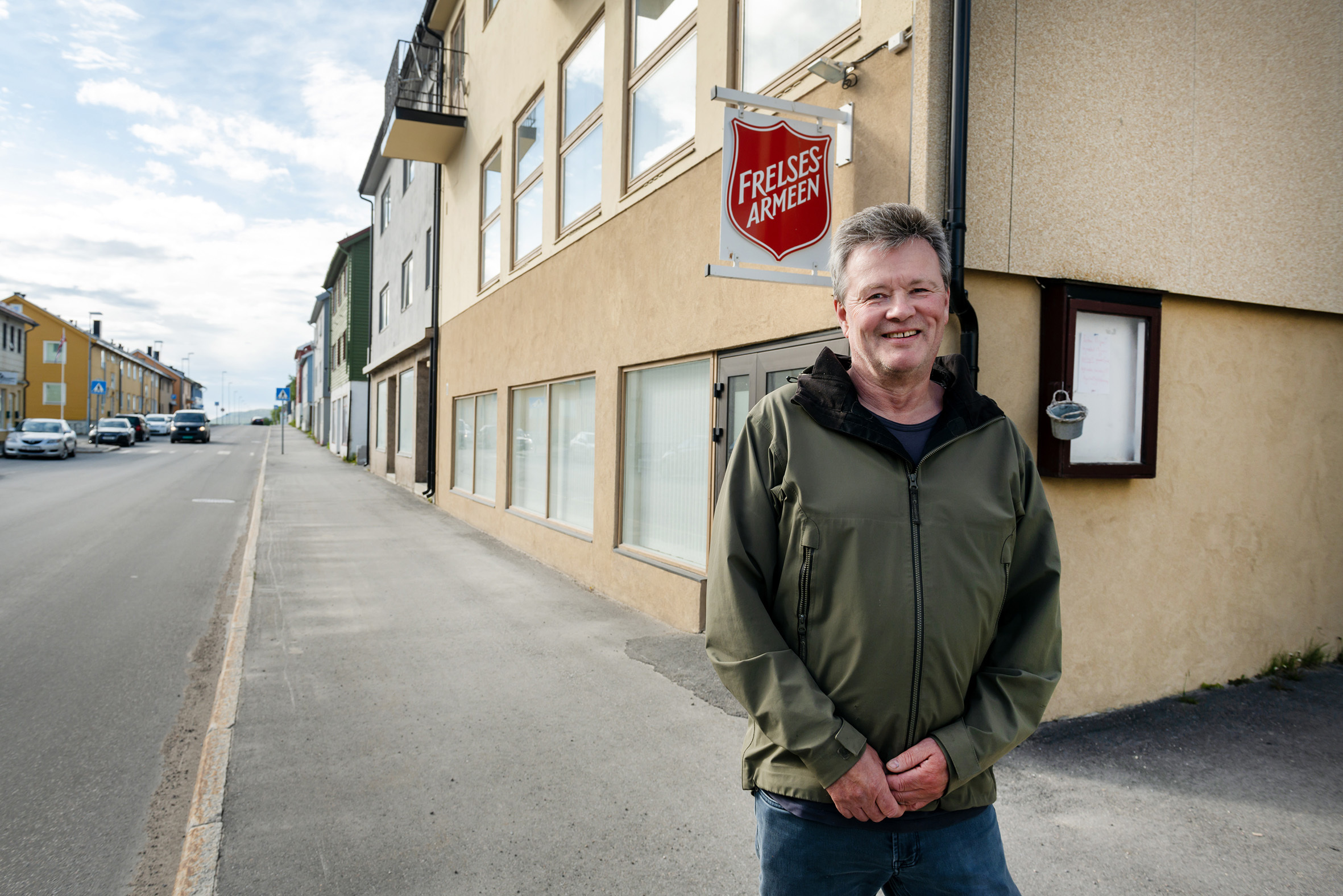 Daglig leder på Stedet Vadsø står utenfor Frelsesarmeen-bygget med skjoldet i bakgrunnen.