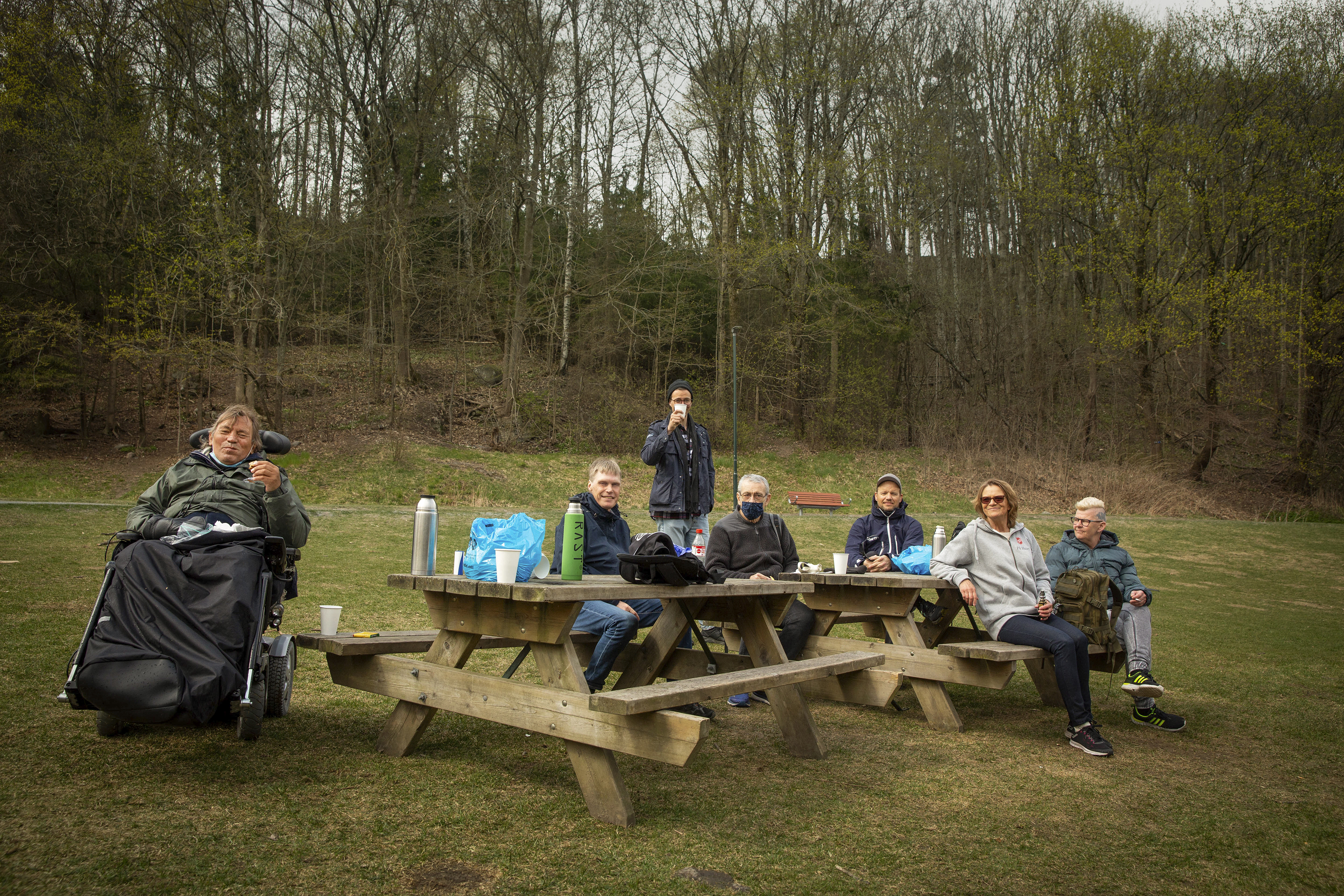 Turgruppen er samlet rundt et bord og spiser nistepakken og drikker kaffe