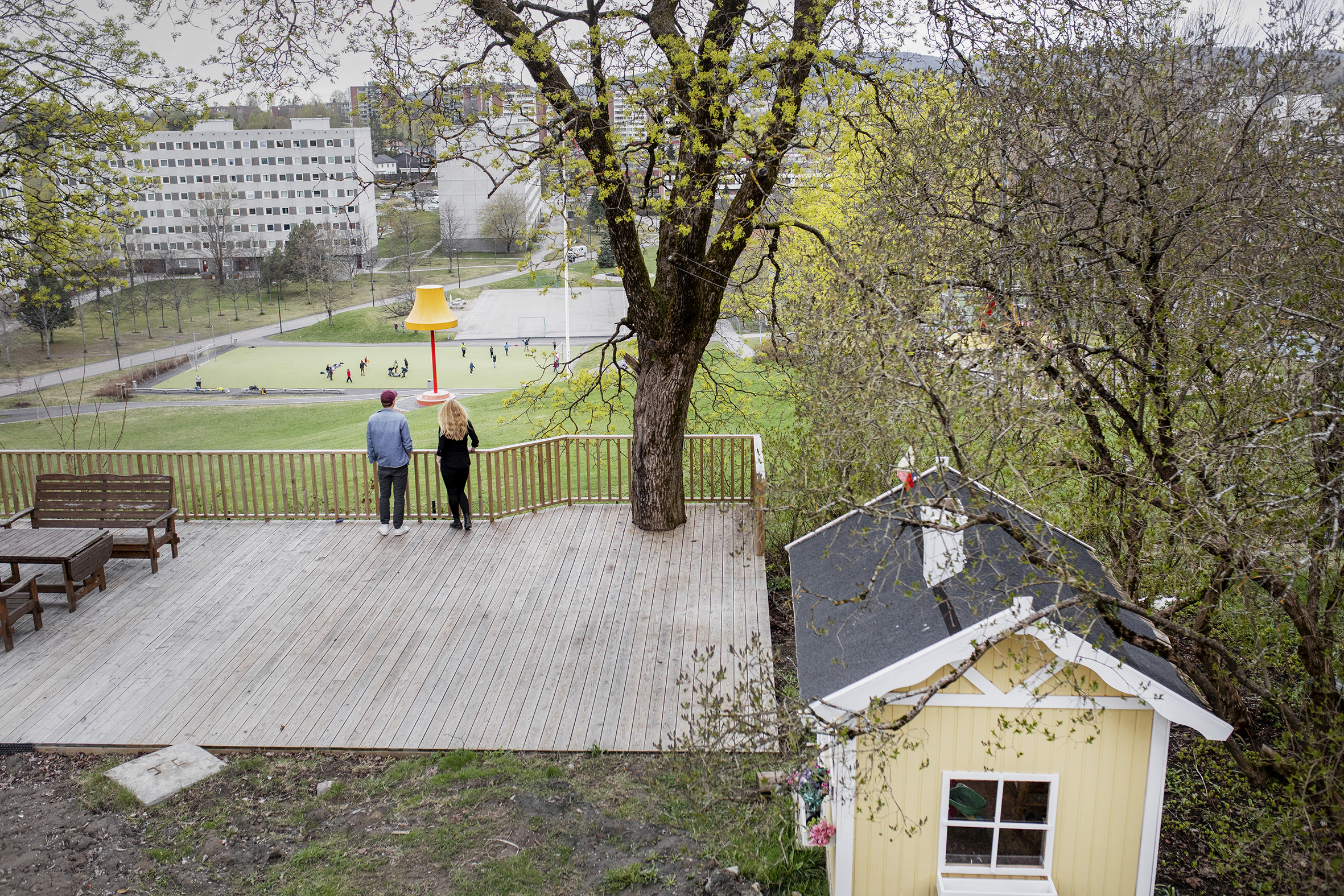 Bildet viser det unge ekteparet som står på en stor platting på den nedre delen av gårdseiendommen. De speider utover området som de har fått ansvaret for.
