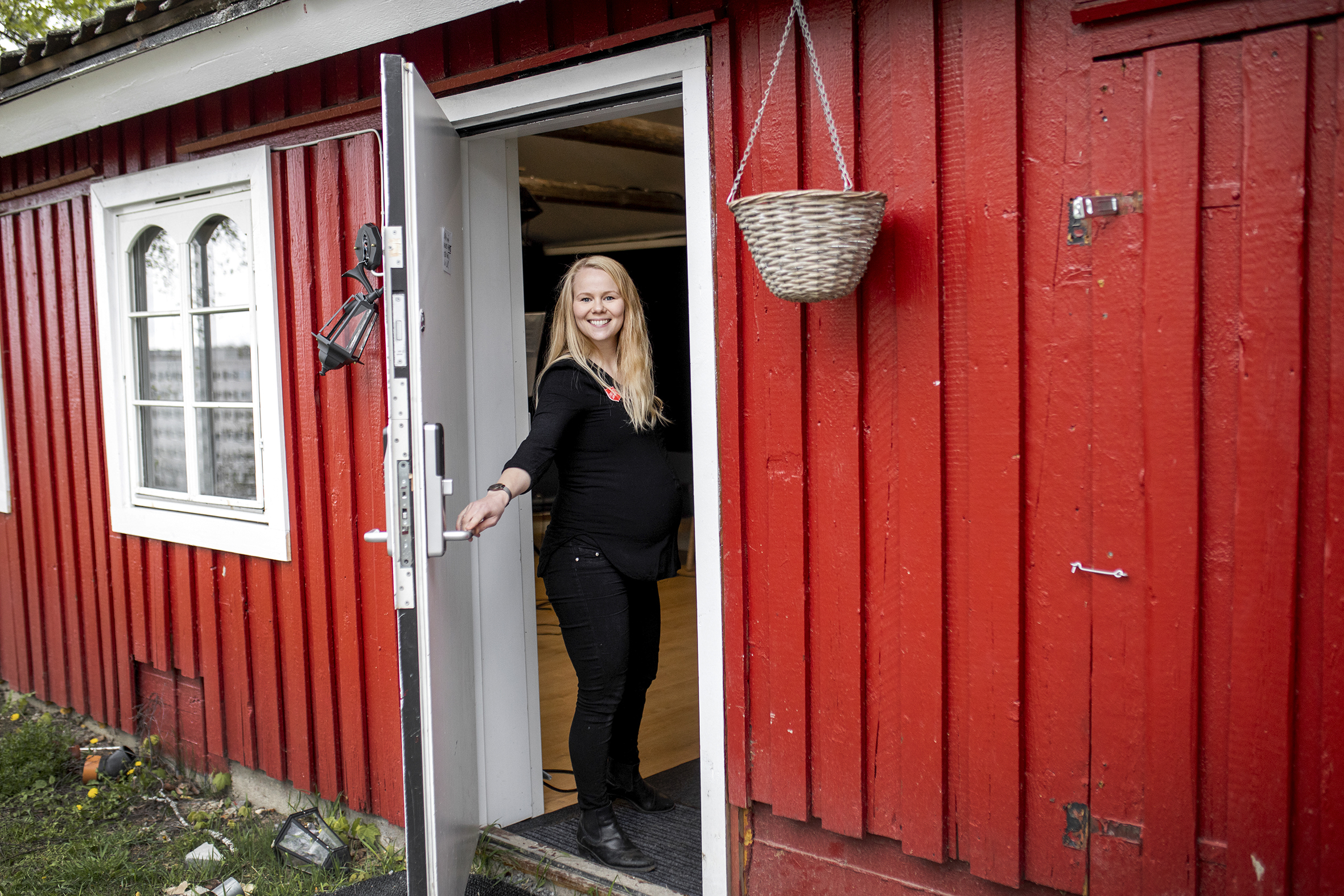 Thea Karlsdóttir Welander står i døråpningen inn til det nye studioet som har kommet på plass i et lite, rødt hus på gårdstunet. Hun smiler til kameraet.