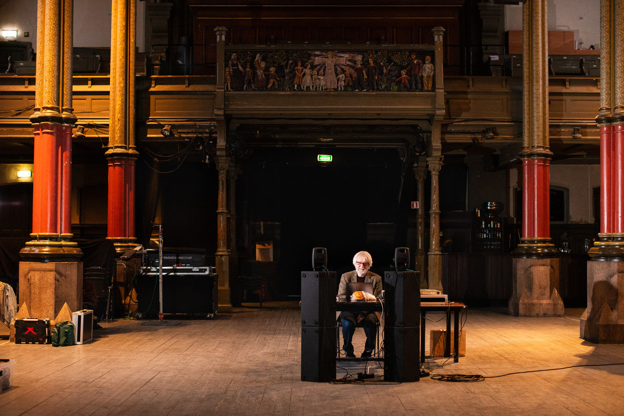 En mann med grått hår sitter på en pult midt i et stort kirkerom