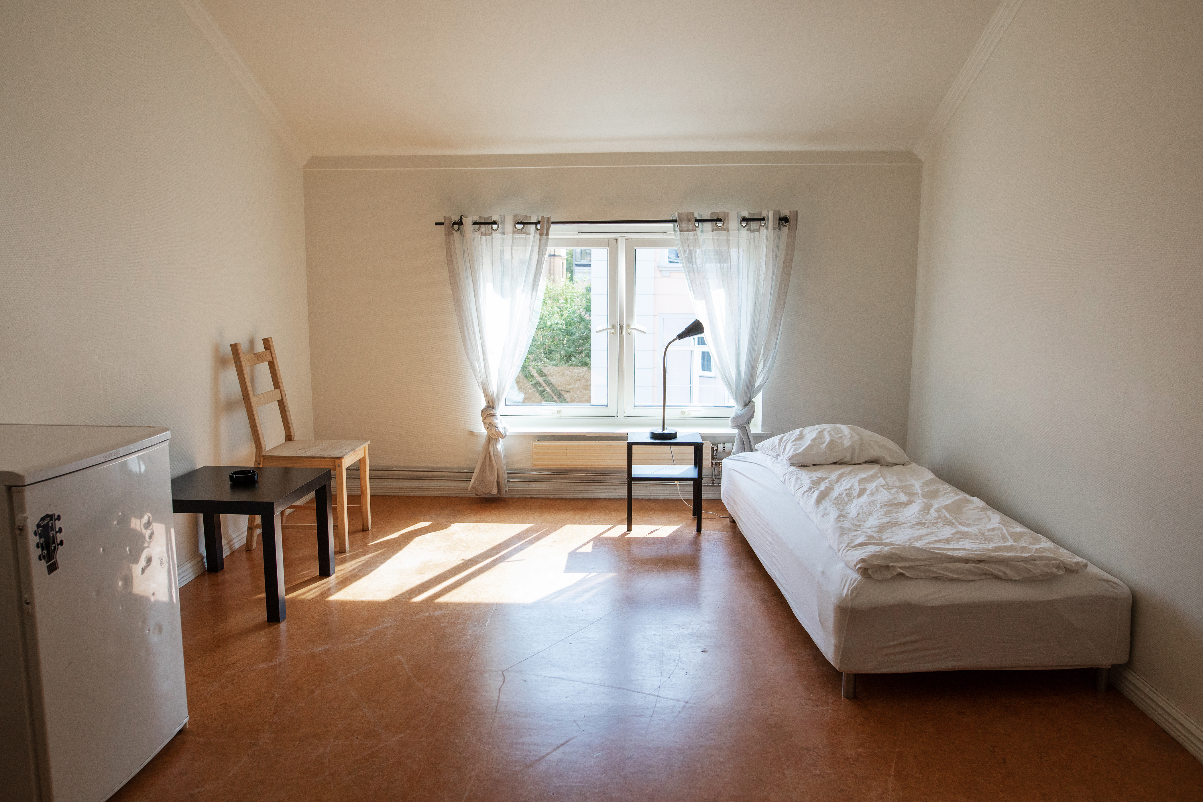 Rommene er enkle men rene. En seng, nattbord et kjøleskap, stol og bord.