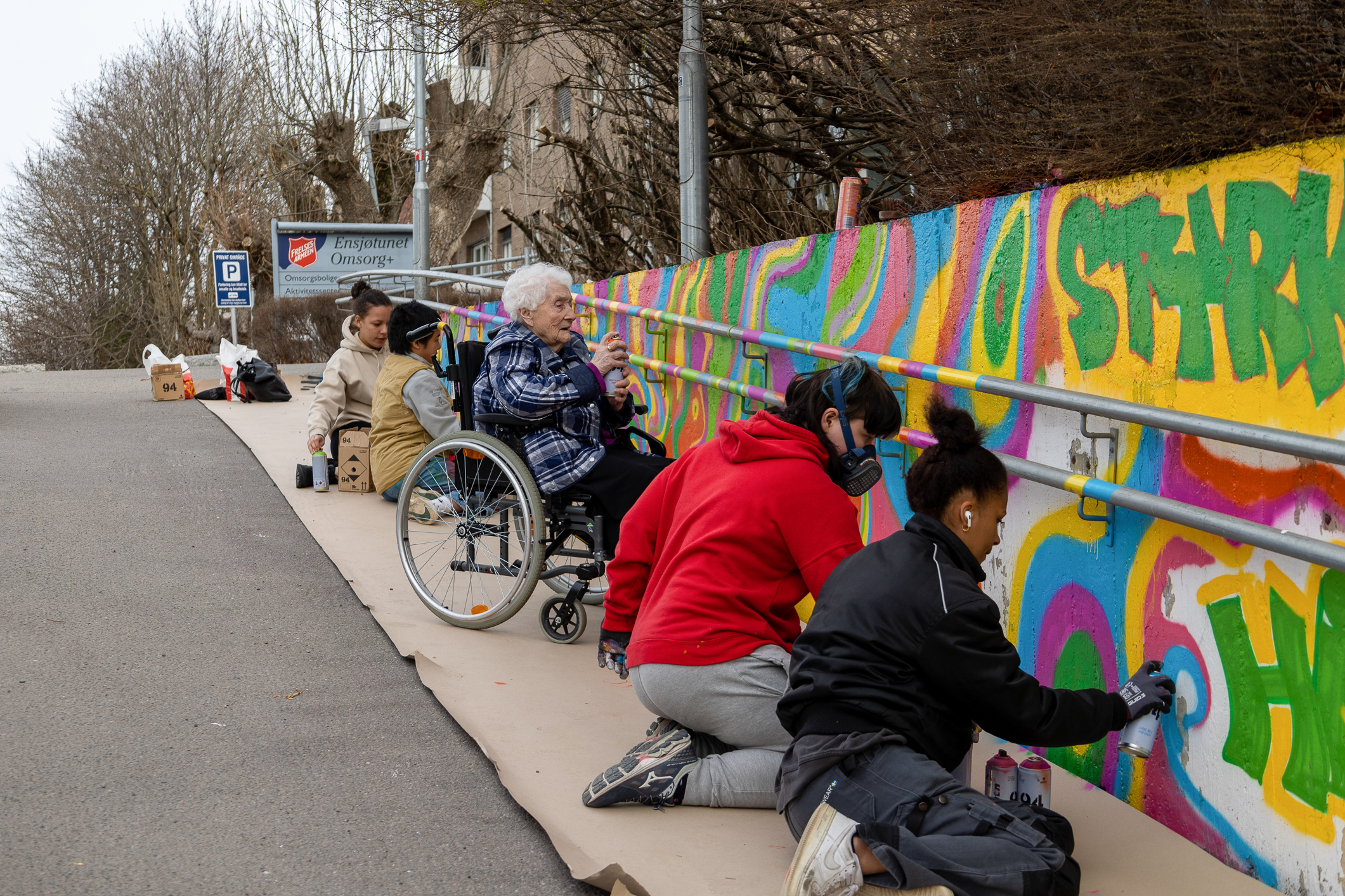 Langs muren er både elever og beboere i gang med sprayboksene.