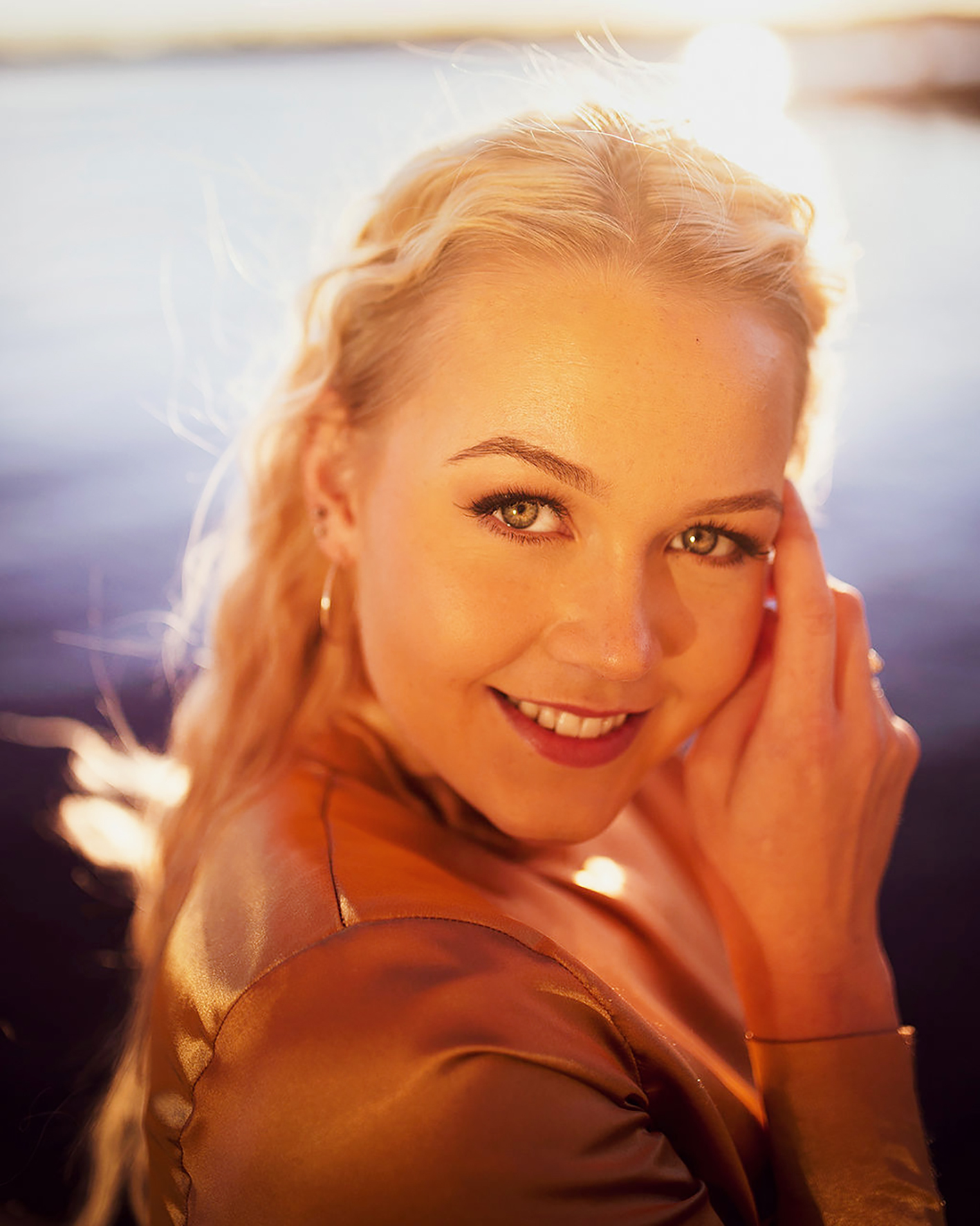 Bildet er et nærbilde, Sunniva står mot siden og snur seg mot kamera og smiler mens hun holder en hånd opp mot ansiktet.