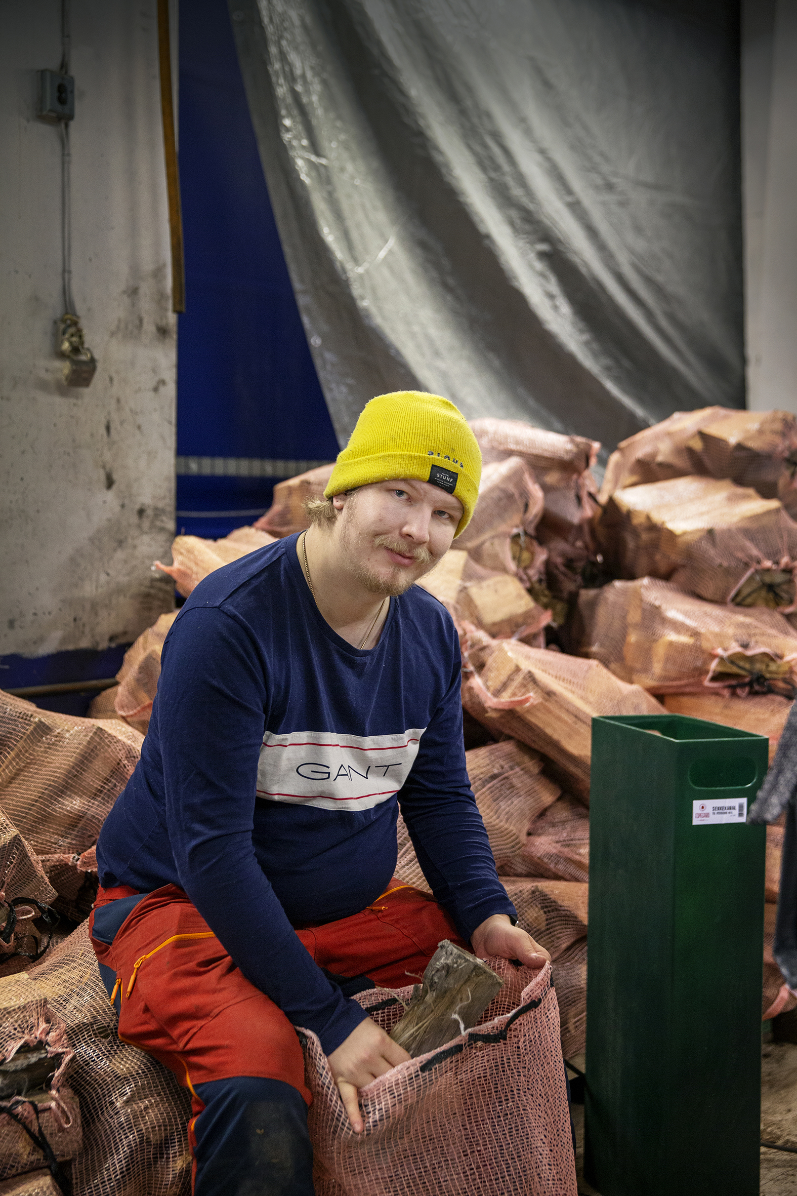 Ryan André Amundsen sitter på en stabel med ved